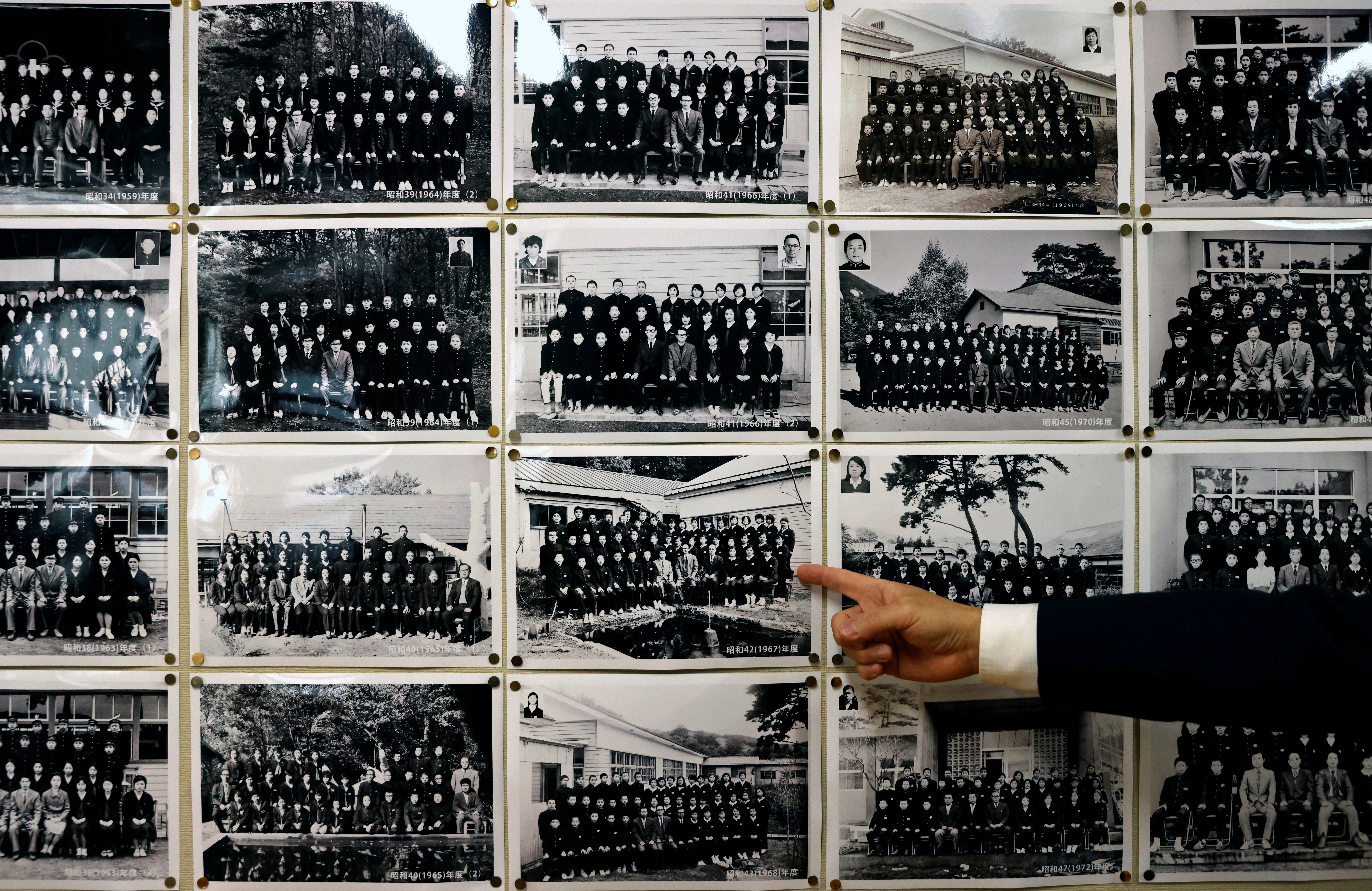 Yumoto Junior High School’s principal Mikio Watanabe, 54, points at old graduation photographs