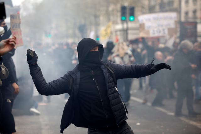 <p>A protester throws a stone at riot police in Paris</p>