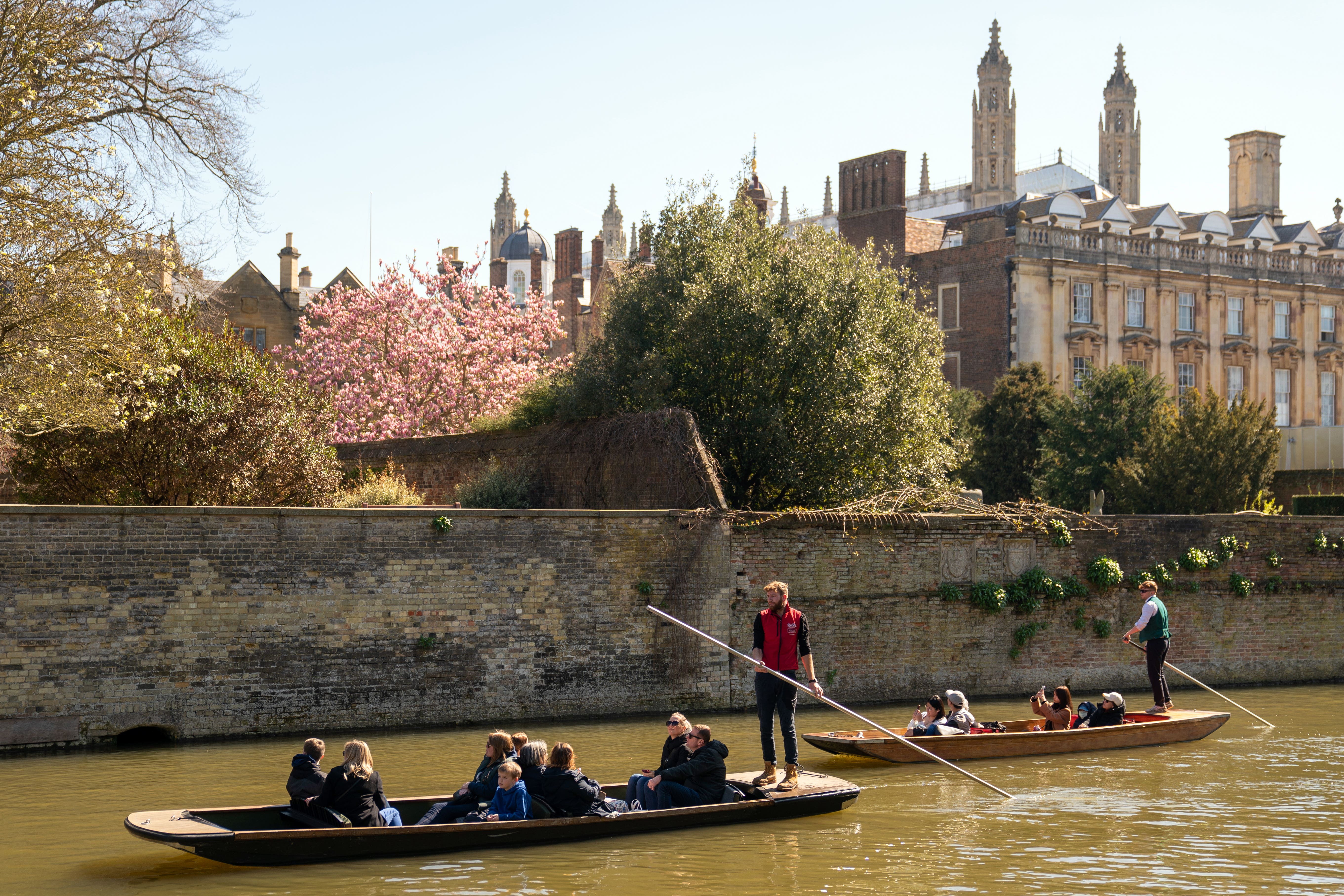 People enjoy a punt tour past Clare College along the River Cam in Cambridge
