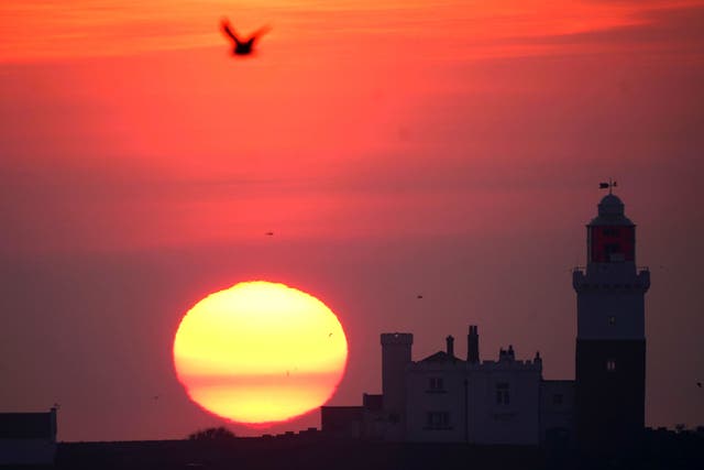 The sun rises behind Coquet island lighthouse, which sits 1.2km off the Northumberland coast near Amble (Owen Humphreys/PA)