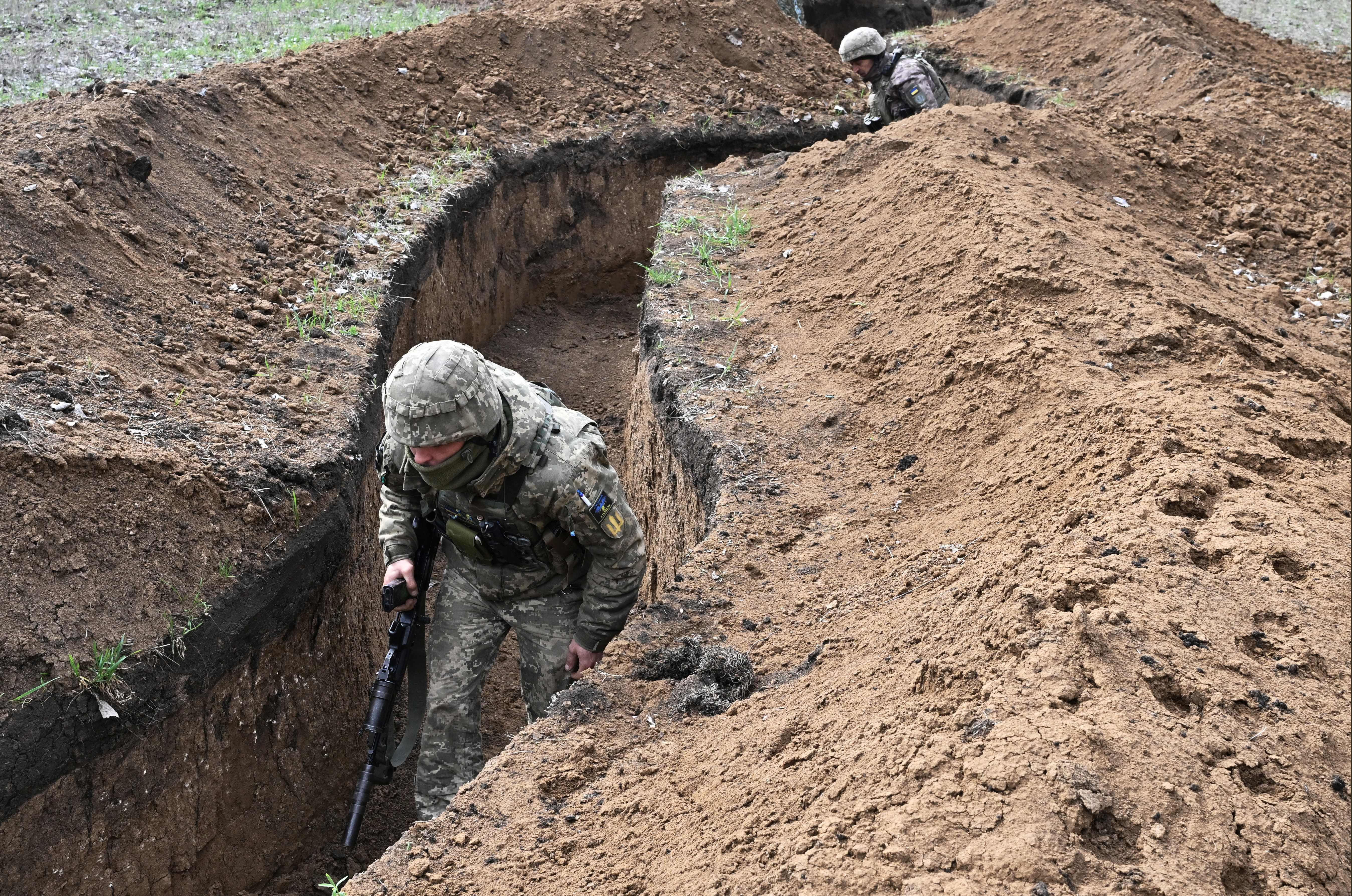 <p>Ukrainian servicemen walks along trenches near the town of Bakhmut on Saturday</p>