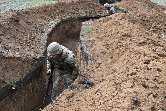 <p>Ukrainian servicemen walks along trenches near the town of Bakhmut on Saturday</p>
