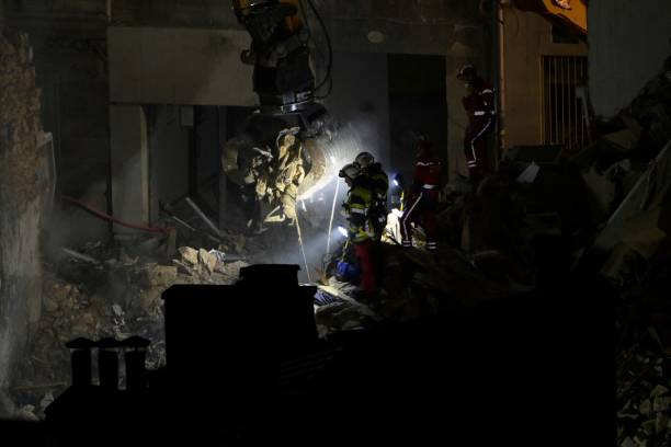 Emergency service personnel watch as an excavator moves rubble at ‘rue Tivoli’ after a building collapsed in the street, in Marseille, southern France, on 9 April 2023