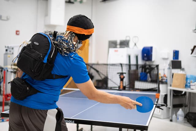 A research participant plays against a ball-serving machine while his brain is imaged with an EEG cap (Frazier Springfield/University of Florida/PA)