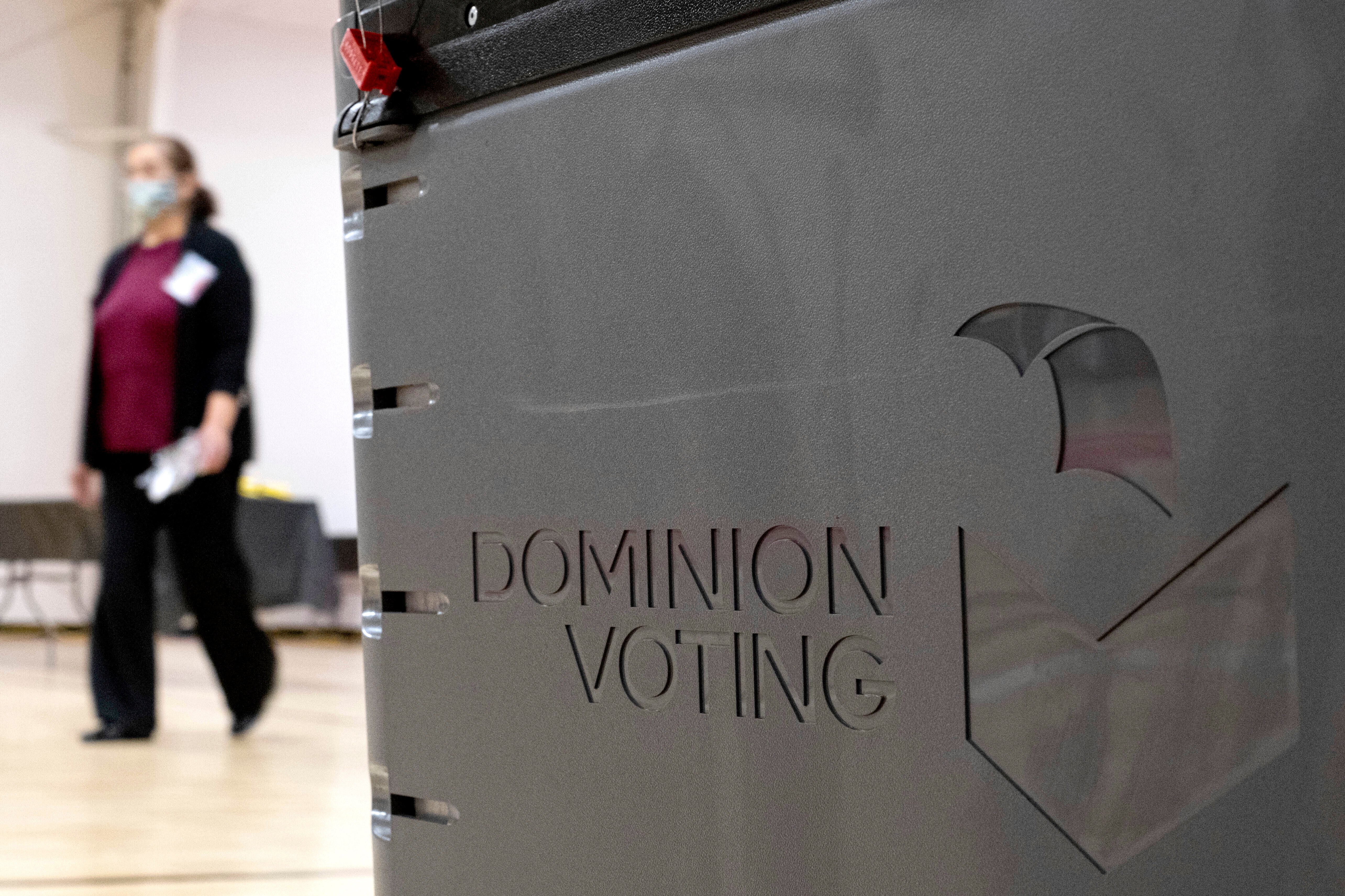 File. A worker passes a Dominion Voting ballot scanner while setting up a polling location at an elementary school in Gwinnett County, Ga., outside of Atlanta, on 4 January 2021