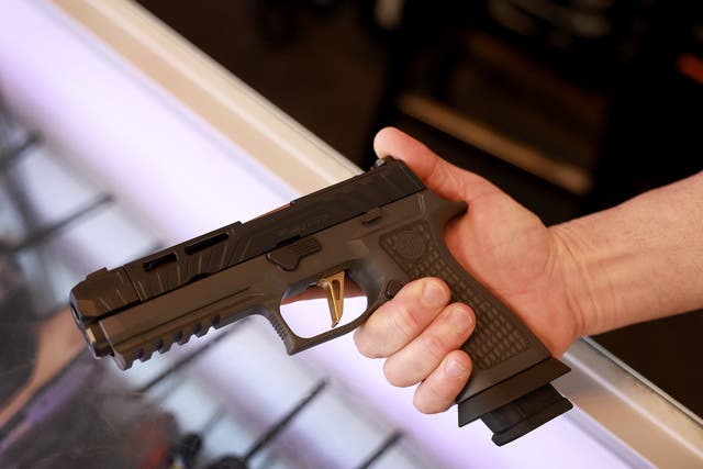 <p>A Sig Sauer P320 handgun is held at the WEX Gunworks store in Delray Beach, Florida</p>