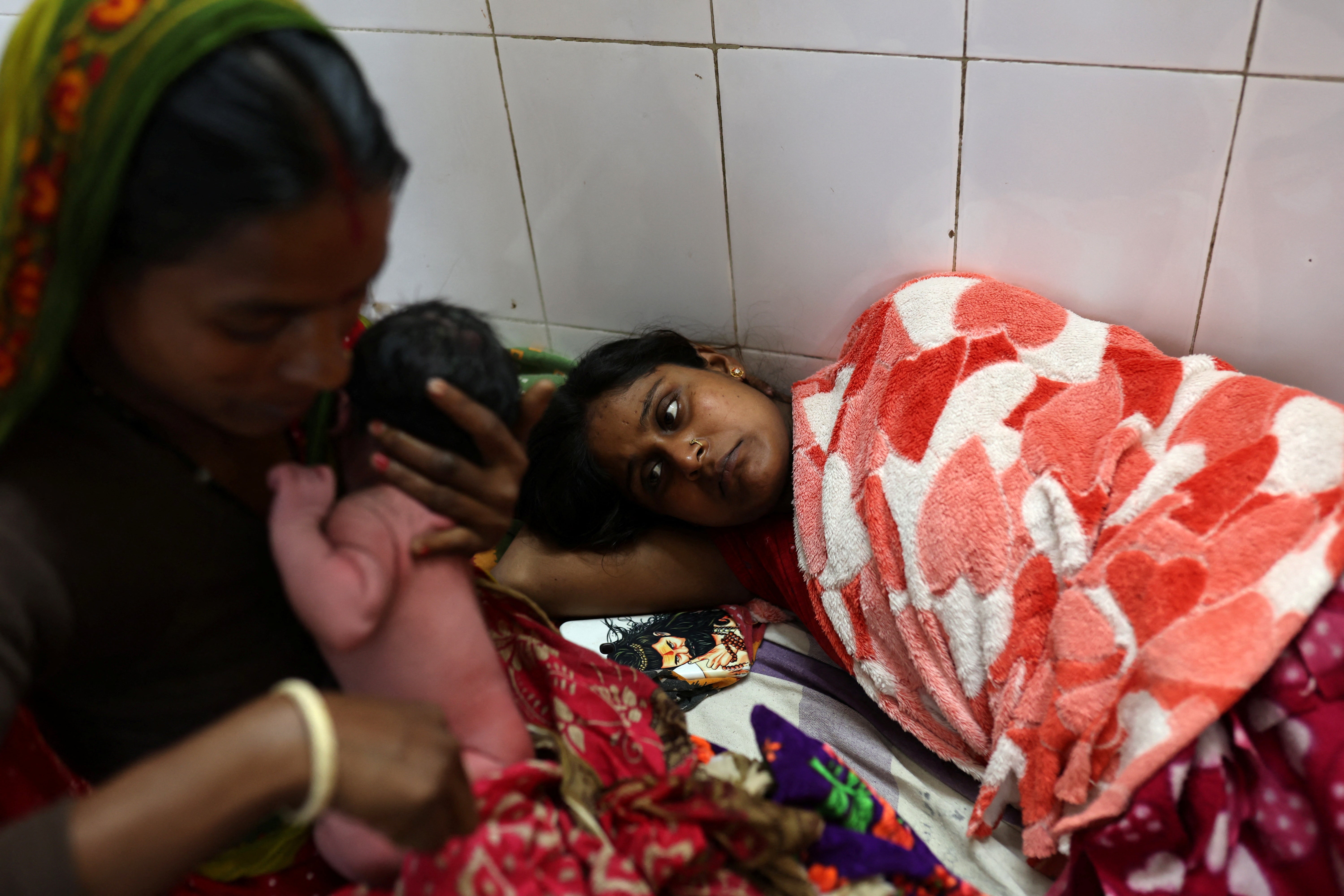 Chandani Devi rests as her mother, Ranjana, holds her newborn daughter