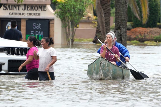 <p>Residents paddle and walk along a flooded road on Thursday in Fort Lauderdale, Florida. Over two feet of rain fell causing widespread flooding, closing the Fort Lauderdale airport and turning thoroughfares into river</p>