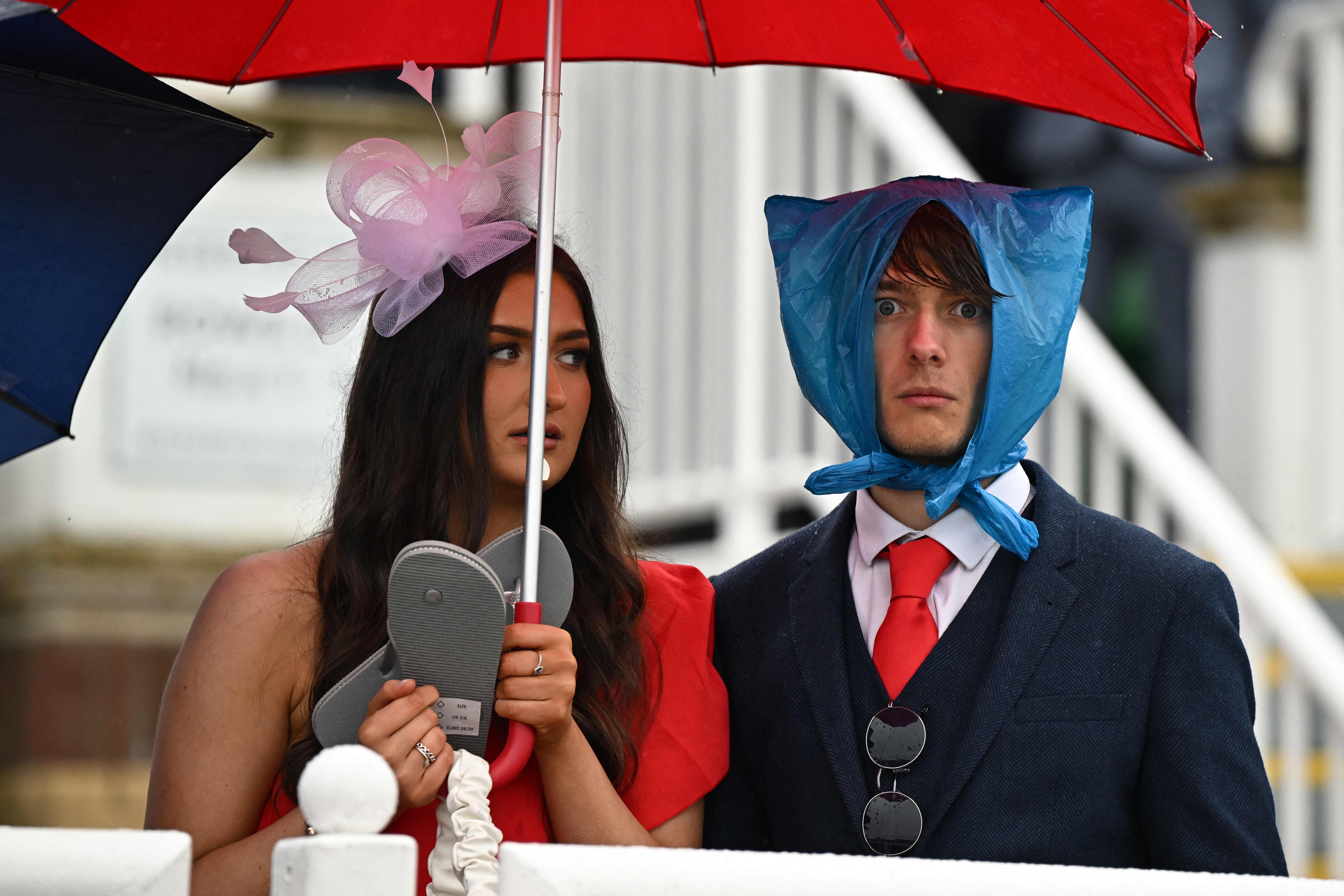 Racegoers shelter from the rain as they attend on the second day of the Grand National Festival horse race meeting at Aintree Racecourse in Liverpool, north-west England