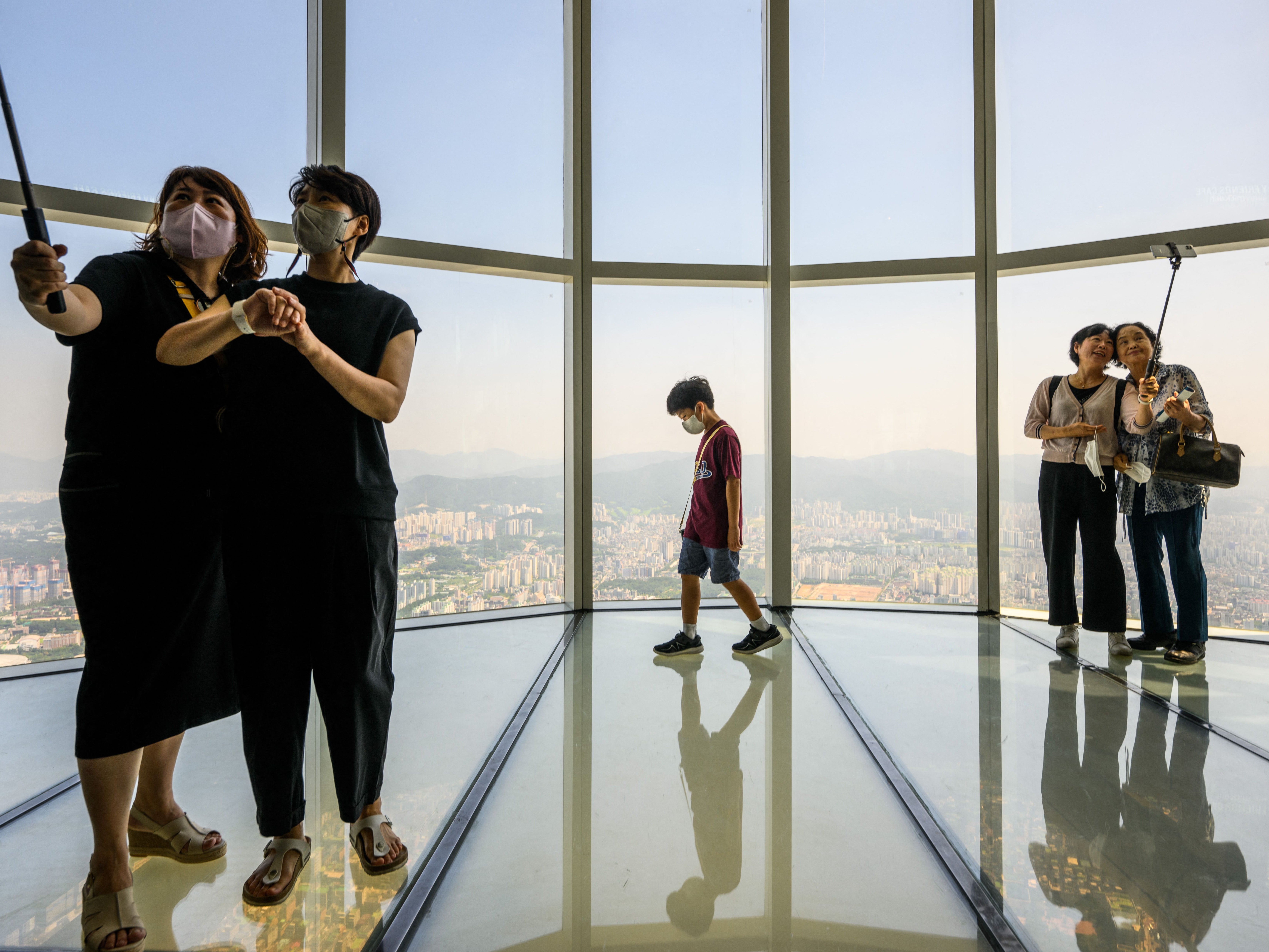 File. People pose for selfies at the Lotte World Tower Seoul Sky on 12 August 2022. - South Korean government has decided to pay an allowance to reclusive youths to help them get out of their homes