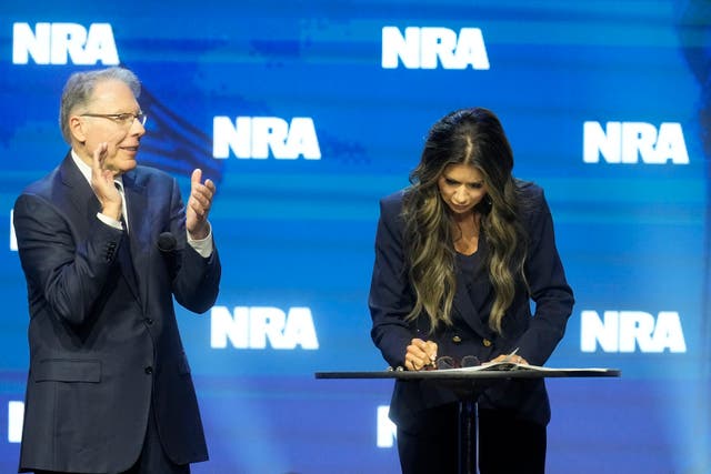 <p>South Dakota Gov. Kristi Noem signs an executive order as Wayne LaPierre, CEO and executive vice-president of the National Rifle Association [L], watches at the National Rifle Association Convention, Friday, 14 April 2023, in Indianapolis </p>