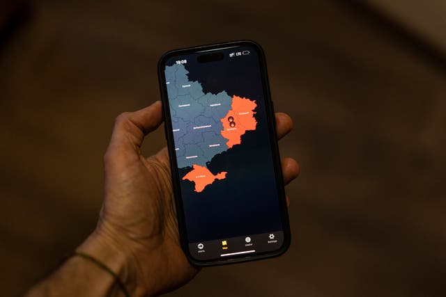 <p>A man takes a photo of his smartphone in Kyiv, Ukraine showing the “Air Alert“ application which shows regions currently under Russian rocket attacks</p>