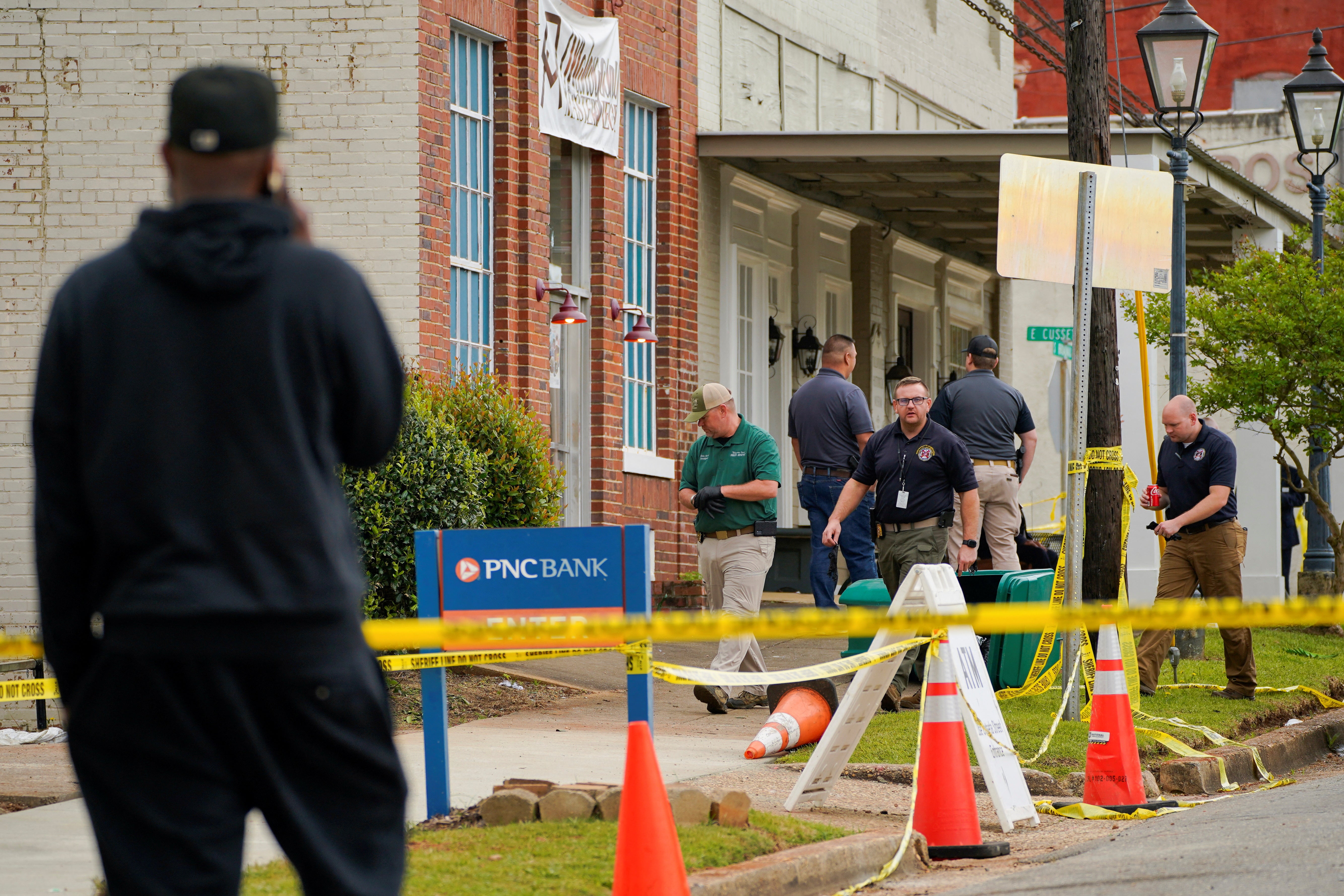 <p>Law enforcement officers walk through the crime scene, a day after the shooting (16 April 2023) </p>