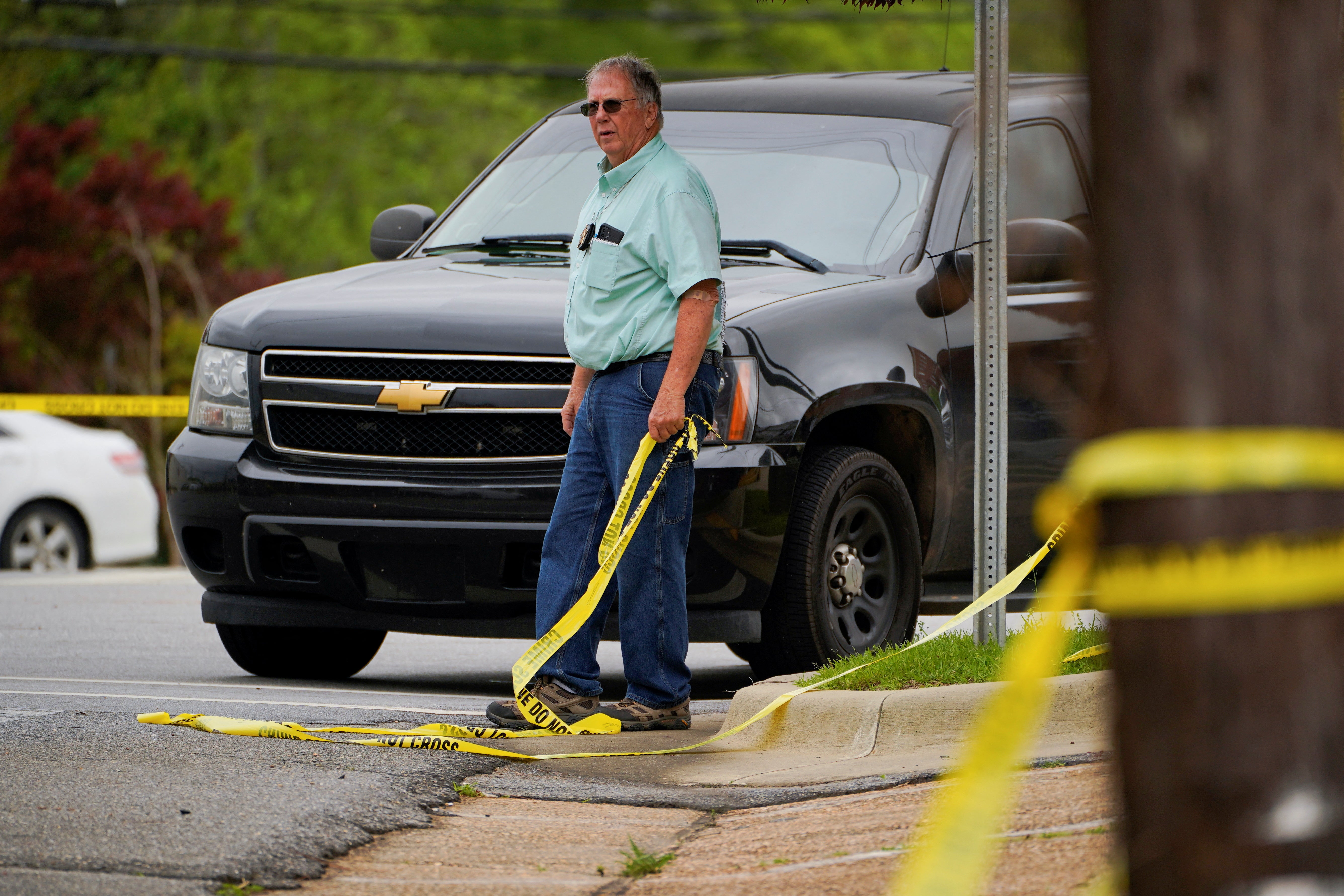 <p>A law enforcement officer holds a piece of crime scene tape</p>