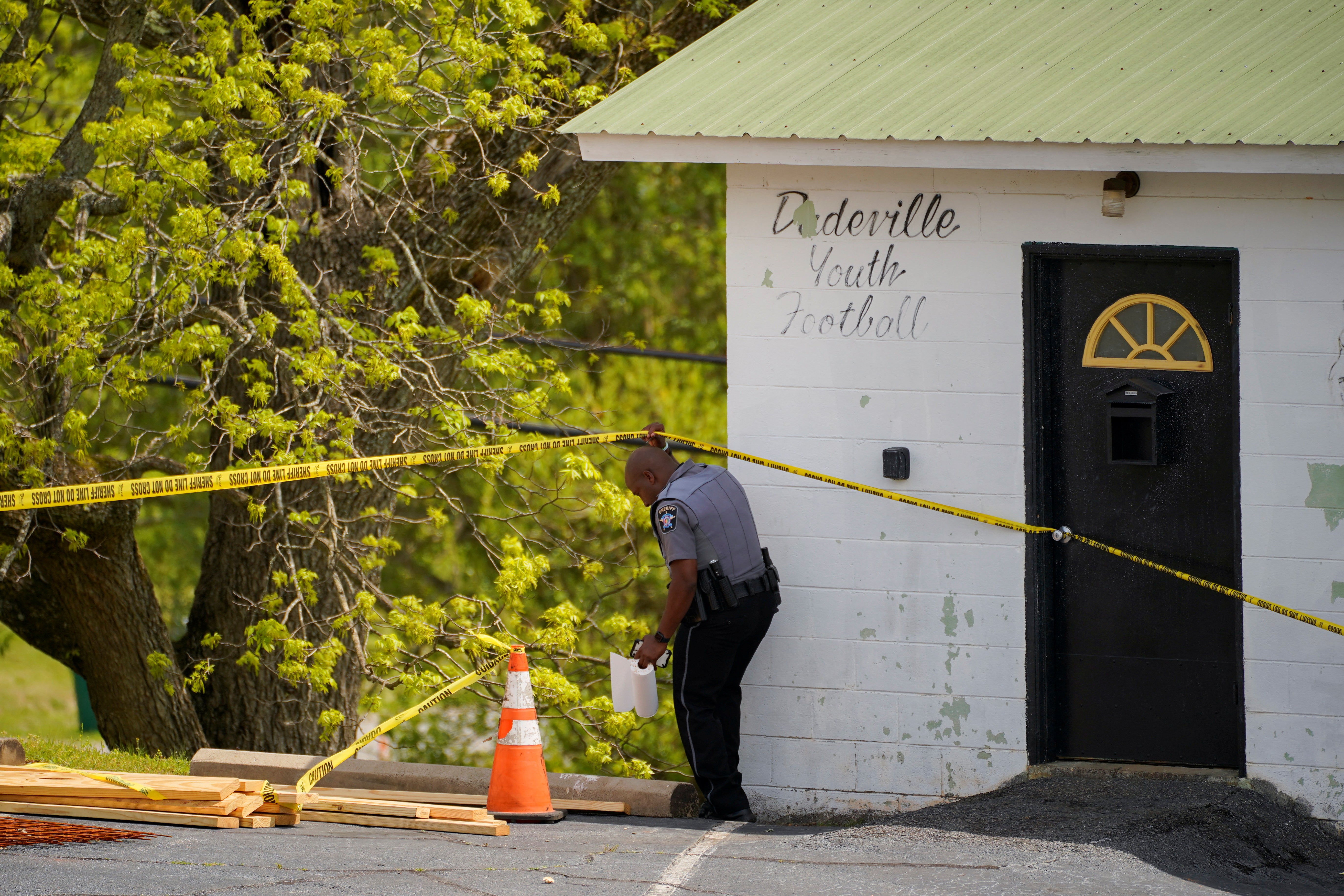 <p>A law enforcement officer goes under a piece of crime scene tape</p>