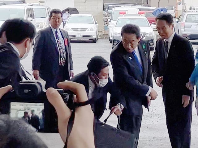 <p>Japanese prime minister Fumio Kishida (second from right) turns as a cylindrical object lands near him at a fishing port in Wakayama, western Japan</p>