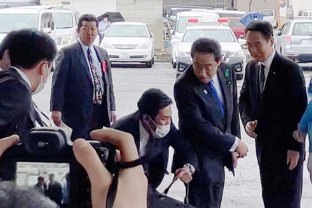 <p>Japanese prime minister Fumio Kishida (second from right) turns as a cylindrical object lands near him at a fishing port in Wakayama, western Japan</p>