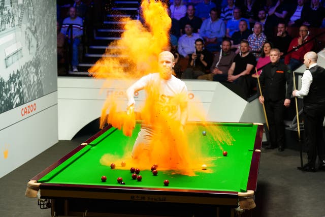 A Just Stop Oil protester jumps on the table and throws orange powder during the World Championship match between Robert Milkins against Joe Perry at the Crucible (Mike Egerton/PA)