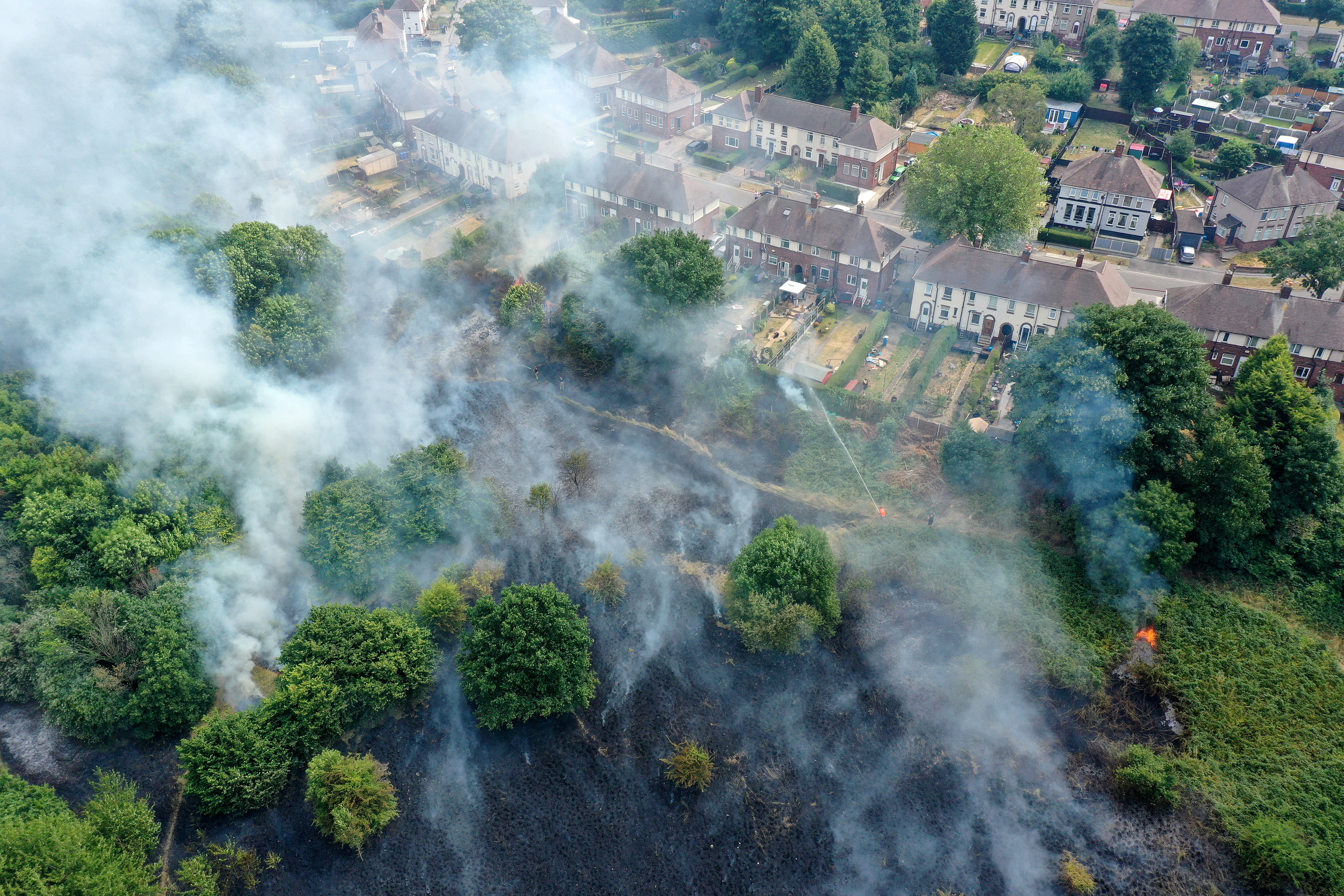 Firefighters contain a wildfire that encroached on nearby homes in the Shiregreen area of Sheffield on 20 July 2022 in Sheffield, England