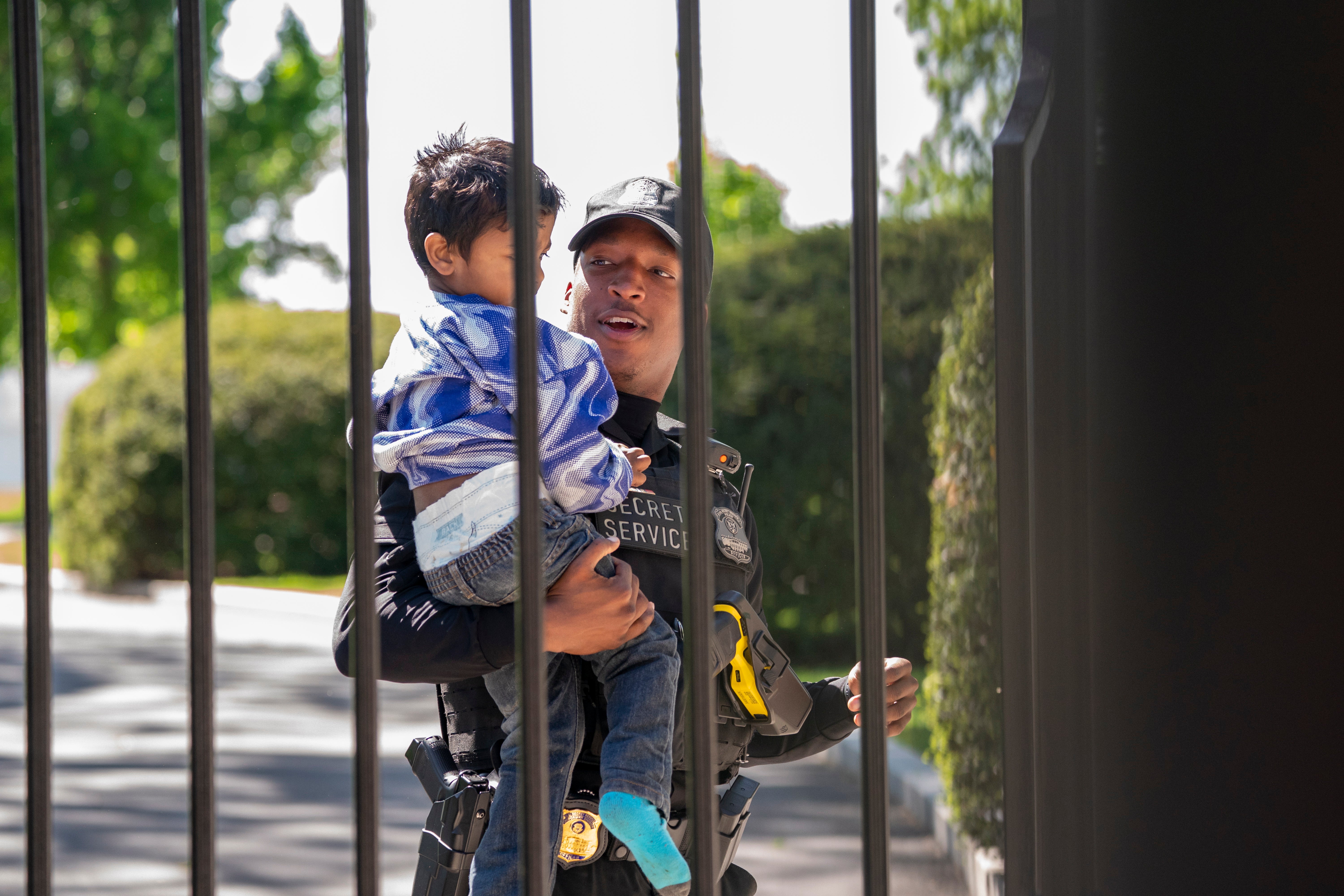 A US Secret Service uniformed division police officer carries a child that climbed through the bars of the White House fence on 18 April 2023
