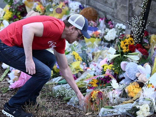<p>A man places flowers at a makeshift memorial for victims at the Covenant School building at the Covenant Presbyterian Church following a shooting, in Nashville, Tennessee, on March 28, 2023</p>