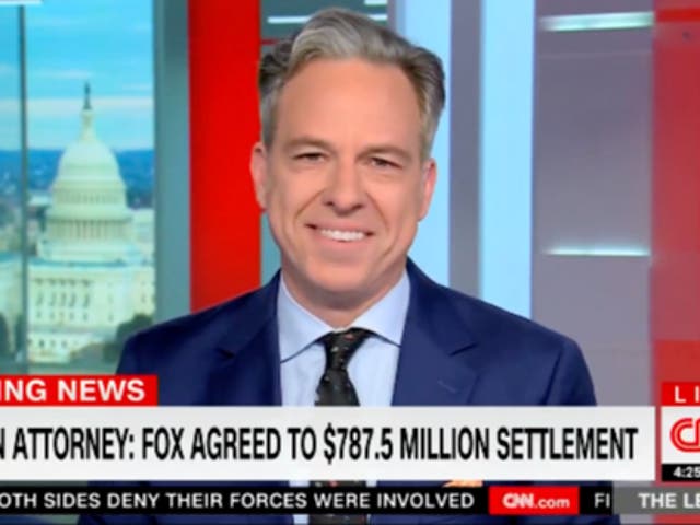<p>Jake Tapper smiles as he reads news of Fox New’s $787m settlement with Dominion Voting Systems</p>