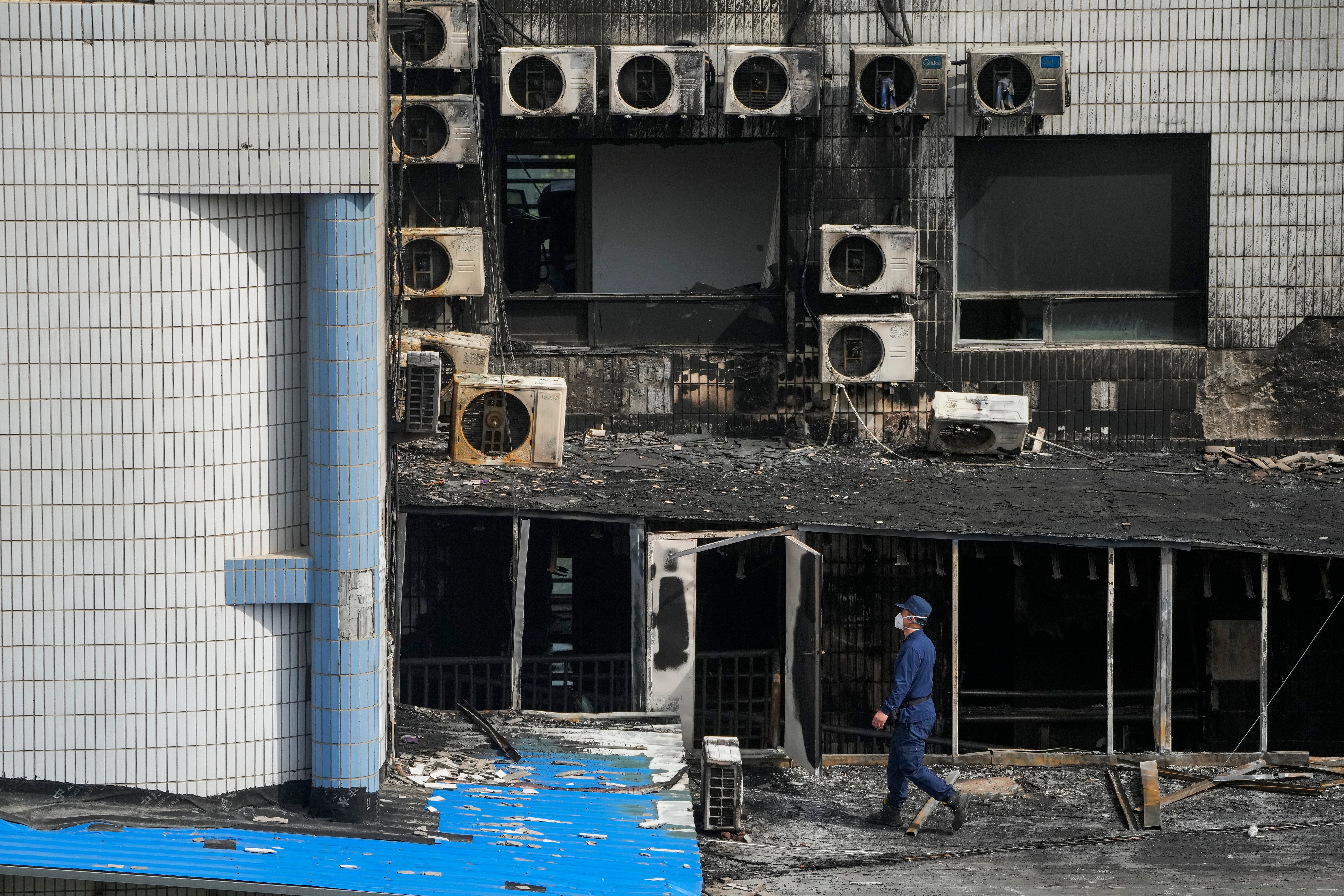 An investigator inspects burnt out area following a fire at a hospital in Beijing