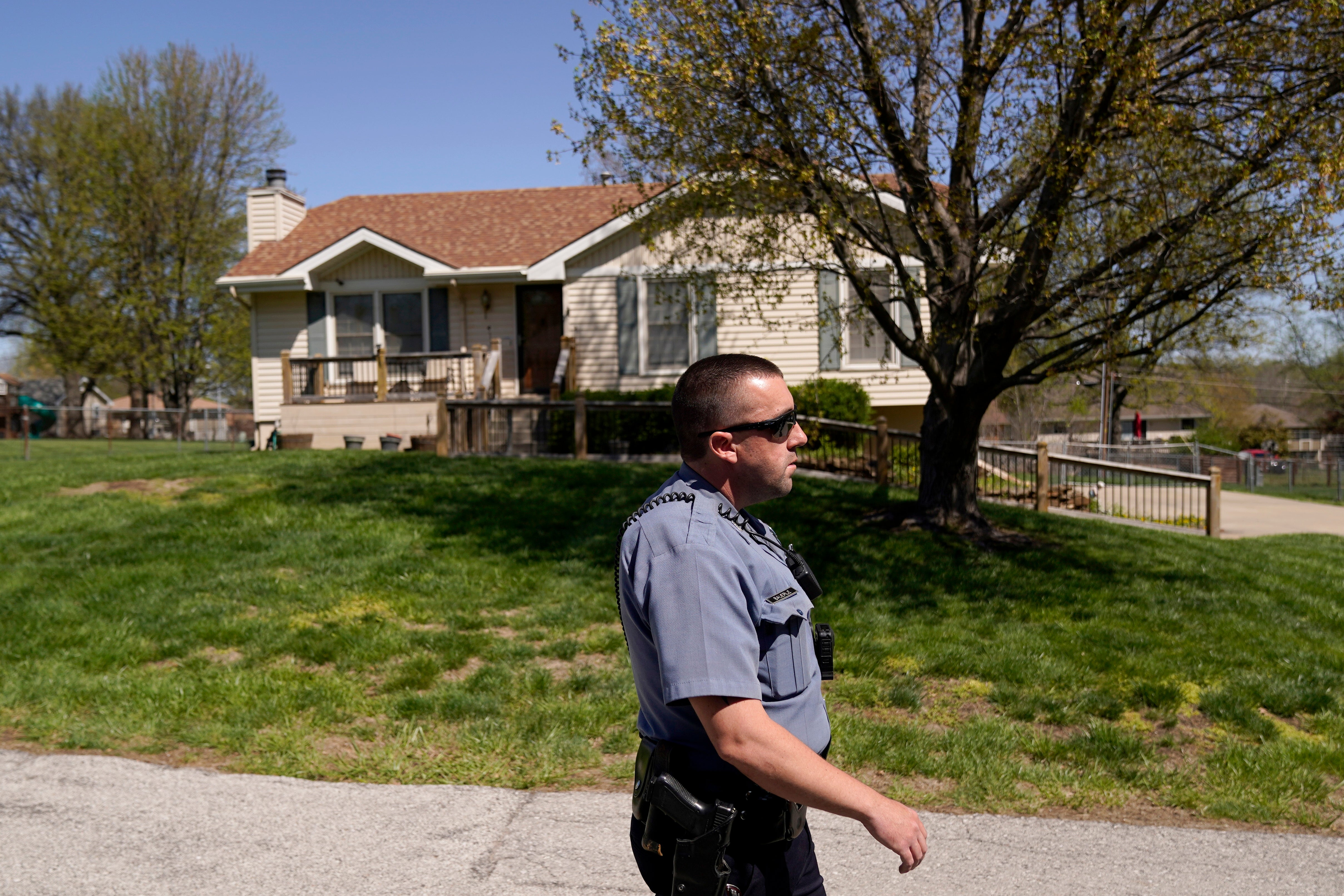 A police officer walks past Andrew Lester’s home