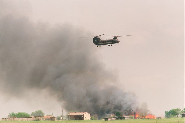 <p>A National Guard helicopter flies past the burning Branch Davidian cult compound in Waco, Texas on 19 April 1993</p>