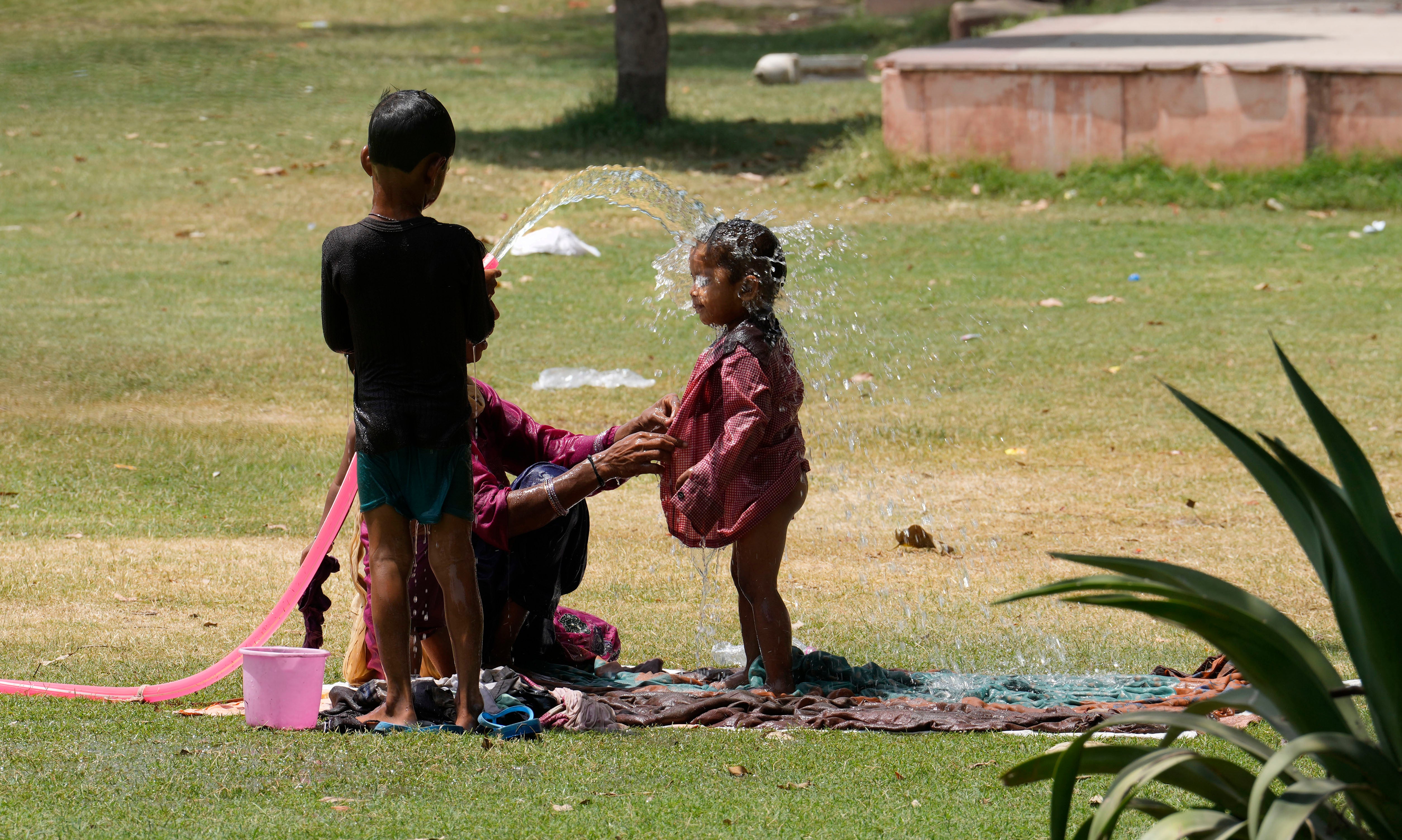 <p>A family cools themself in a park using an irrigation water pipe as northern Indian continues to reel under intense heat wave in Lucknow, Uttar Pradesh on Wednesday, April 19, 2023</p>