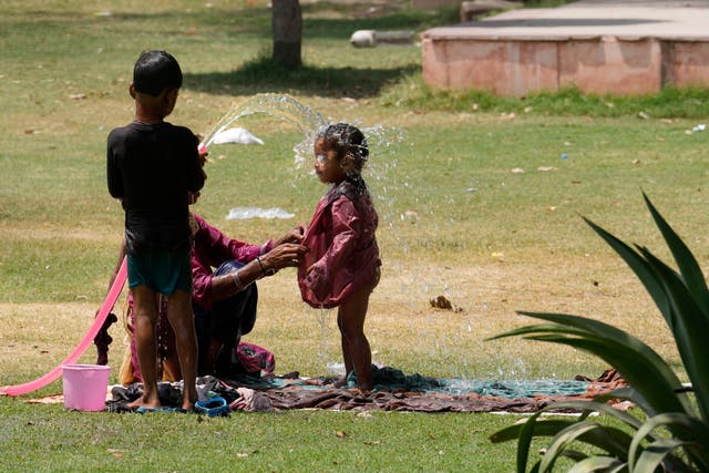 <p>A family cools themself in a park using an irrigation water pipe as northern Indian continues to reel under intense heat wave in Lucknow, Uttar Pradesh on Wednesday, April 19, 2023</p>