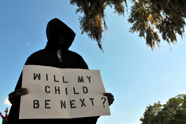<p>A man dressed in a hood holds up a sign saying "Will My Child Be Next?", during a protest march in Sanford, Florida following the 2012 killing of Trayvon Martin </p>