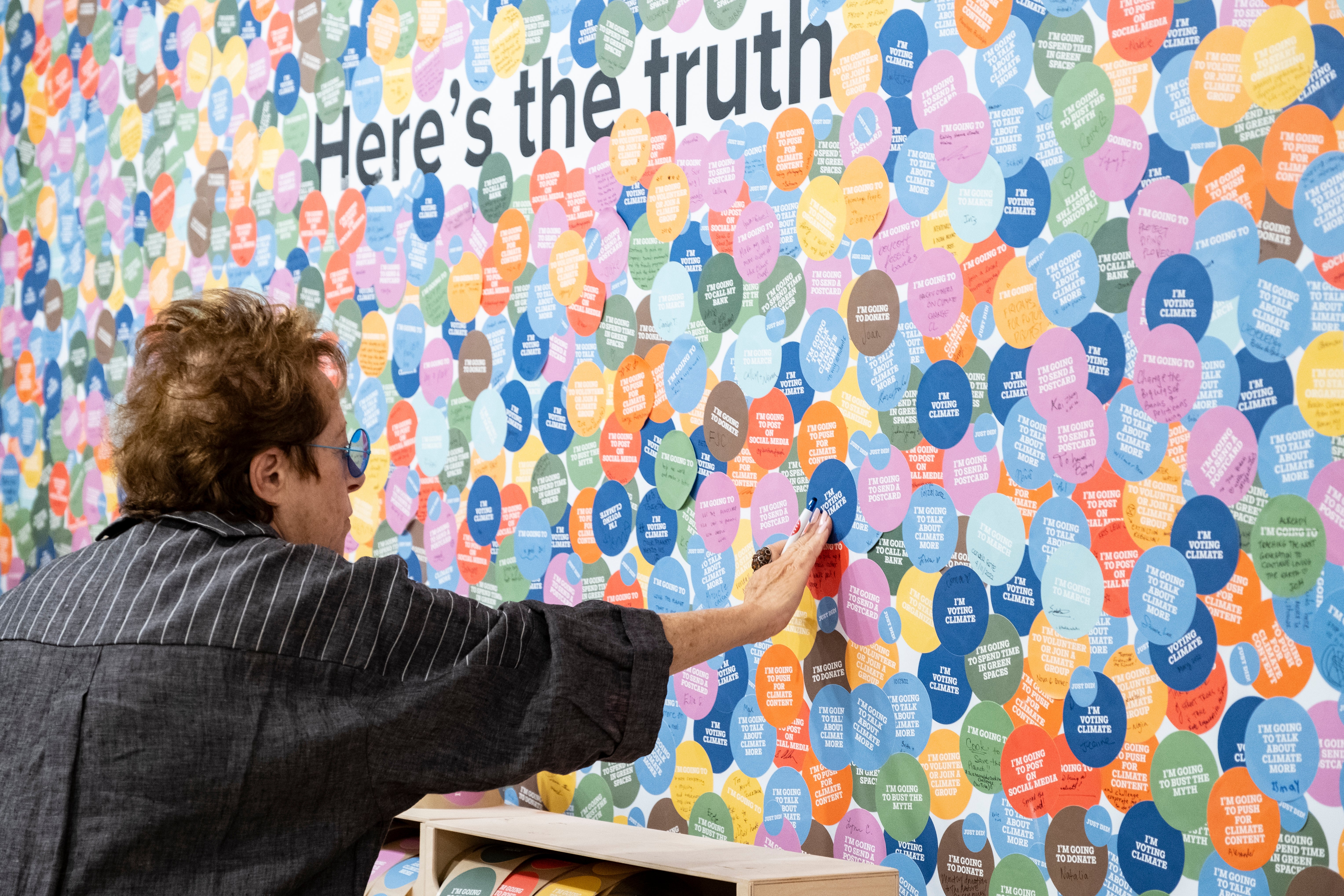 A visitor adds their sticker to the ‘truth wall’ at the Climate Museum