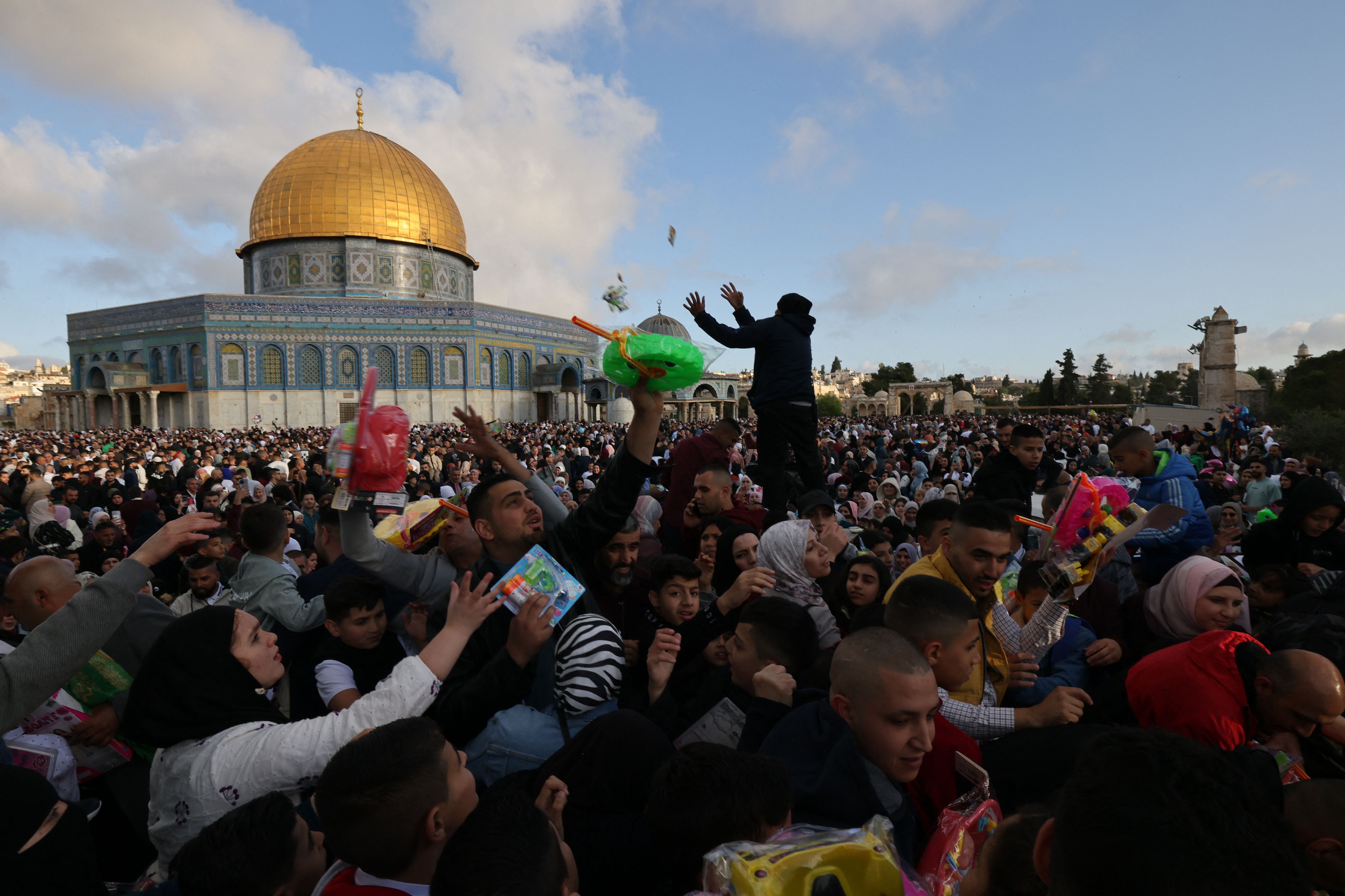 Muslims exchange gifts as they gather on the first day of Eid al-Fitr to celebrate the end of the holy fasting month of Ramadan outside the Dome of the Rock at the Aqsa mosques complex in the Old city of Jerusalem