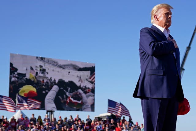 <p>As footage from the Jan. 6, 2021, insurrection at the U.S. Capitol is displayed in the background, former President Donald Trump stands while a song, "Justice for All," is played during a campaign rally at Waco Regional Airport, Saturday, March 25, 2023, in Waco, Texas.</p>