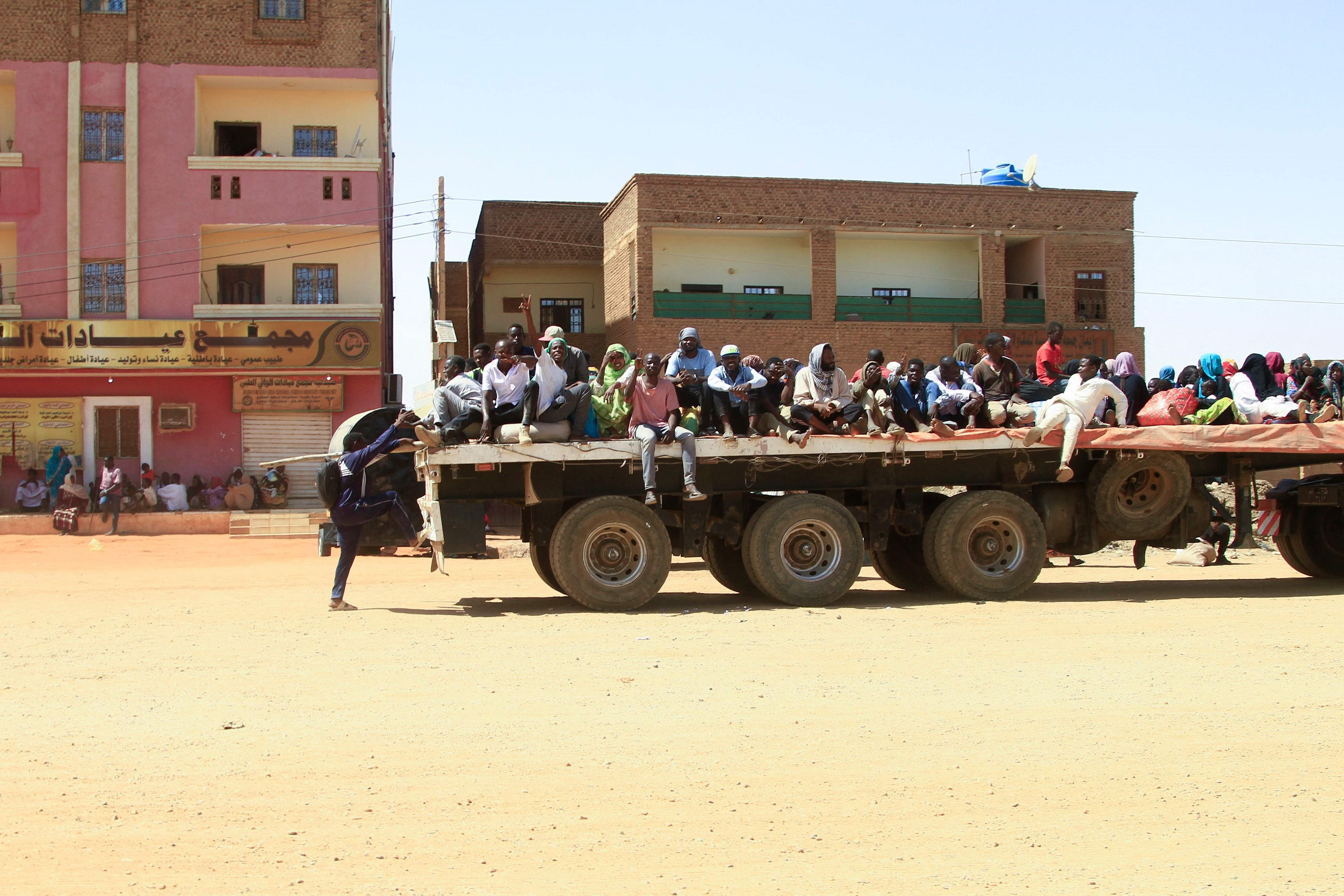 People fleeing a street battle between the forces of two rival Sudanese generals are transported on the back of a truck in Khartoum