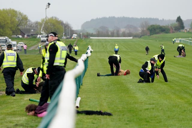 Animal Rising activists are apprehended by police officers as they attempted to invade the race course during the Coral Scottish Grand National festival at Ayr Racecourse (Jane Barlow/PA)