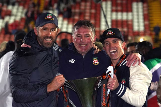 Wrexham co-owners Ryan Reynolds (left), Rob McElhenney (right) and manager Phil Parkinson (centre) celebrate promotion to the Sky Bet League 2 following the Vanarama National League match at The Racecourse Ground, Wrexham. Picture date: Saturday April 22, 2023.