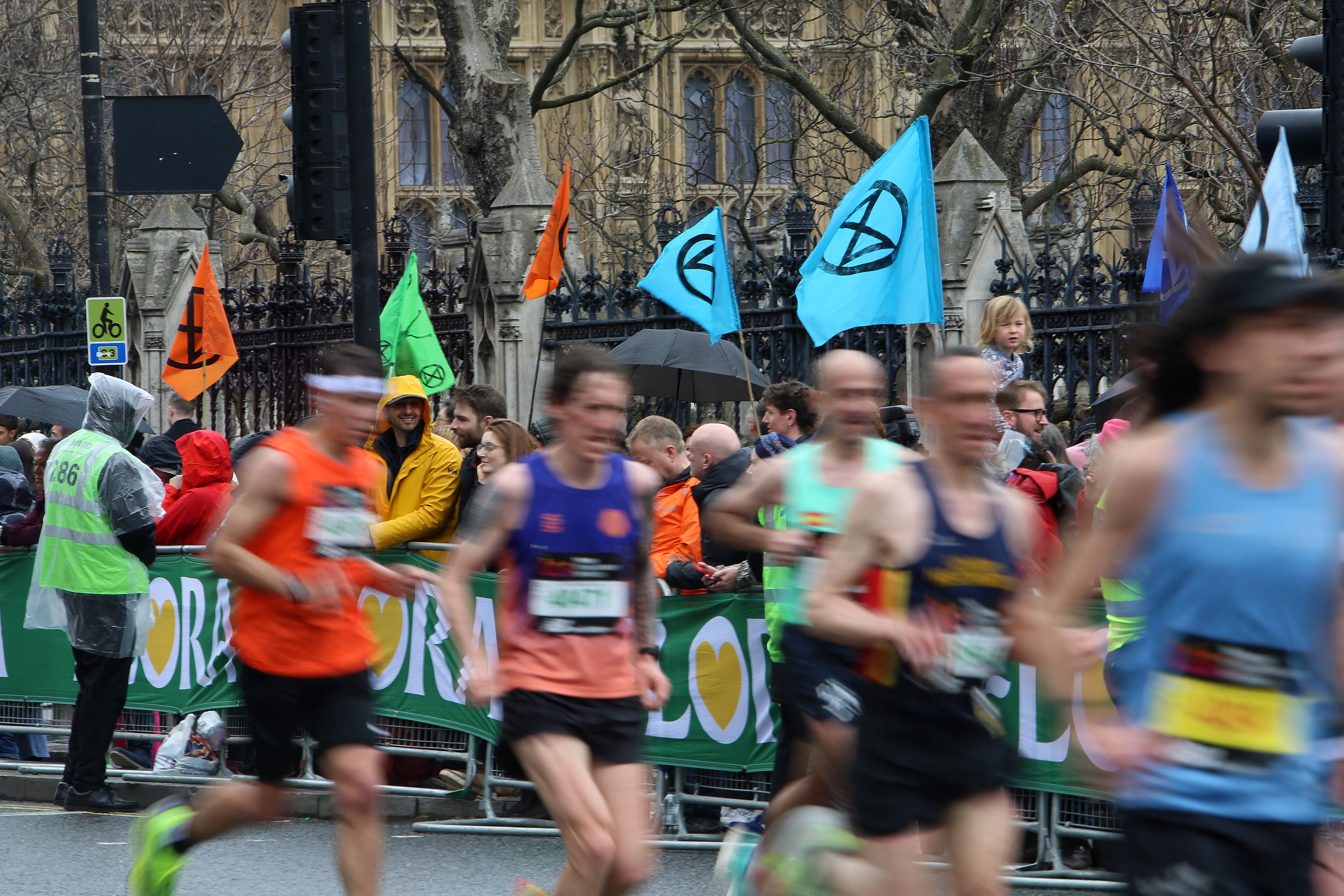 Flags depicting the logo of change protest group Extinction Rebellion are pictured as competitors run past the Palace of Westminster, home of the Houses of Parliament