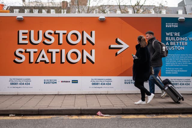 Members of the public walking past signs surrounding the construction site for the London Euston HS2 terminal (Aaron Chown/PA)