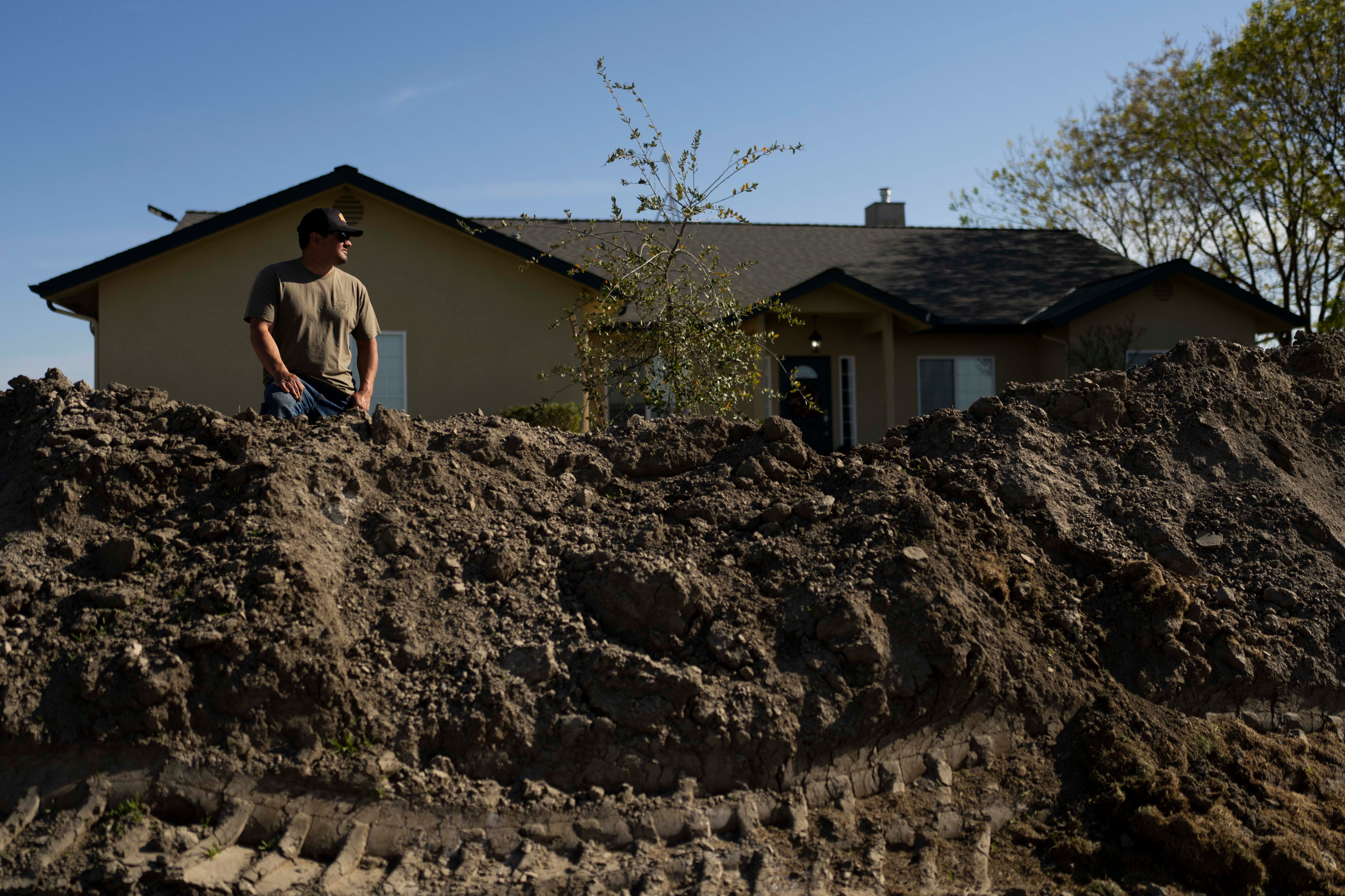 Earl Gomes, 33, stands for a photo outside his home with a berm he built to protect the property from possible flooding in Lemoore, California