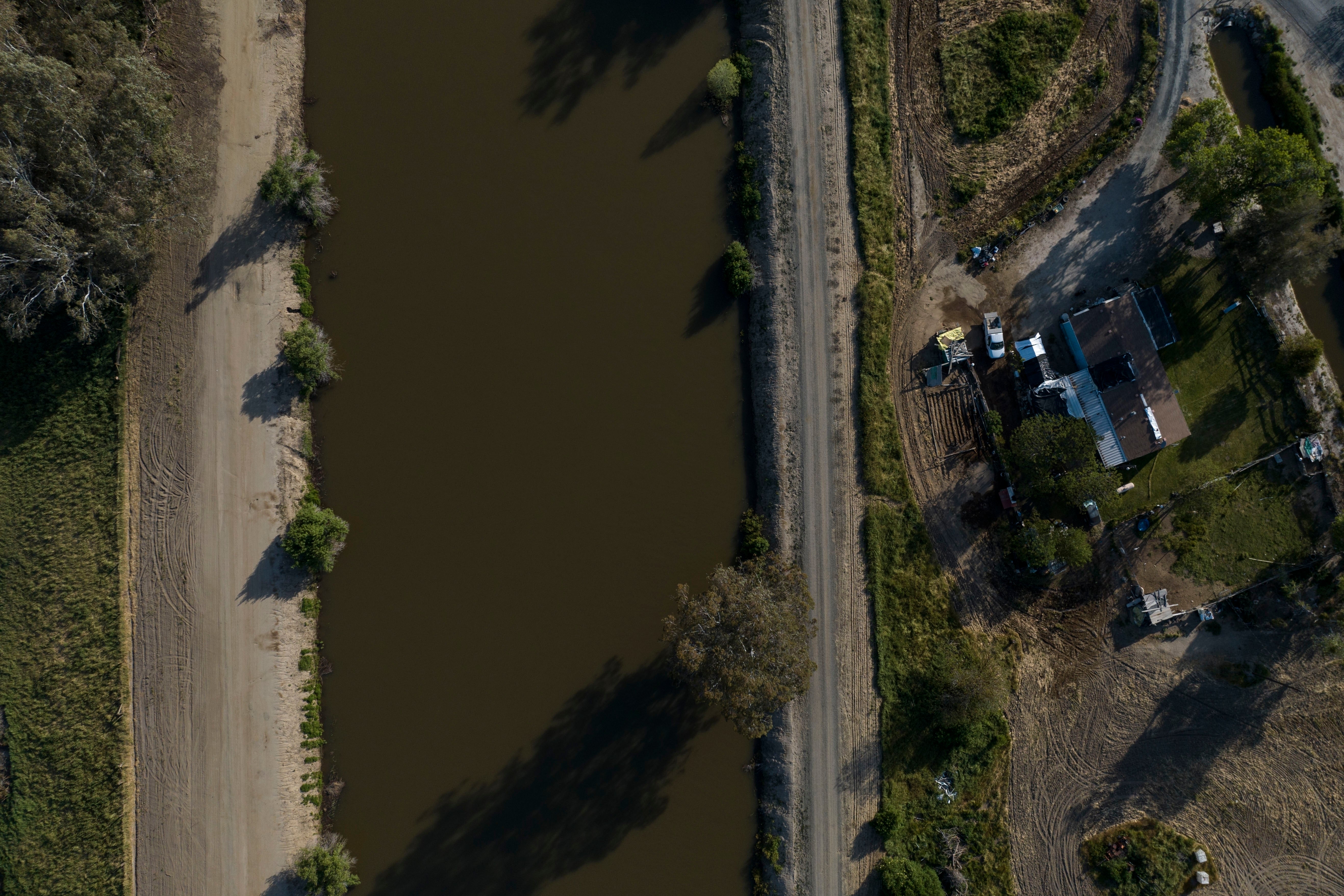 A home sits next to the North Fork Kings River in the Island District of Lemoore, Calif., Wednesday, April 19, 2023. Residents in rural communities in the heart of the state are facing the prospect of being marooned by rising rivers or flooded out