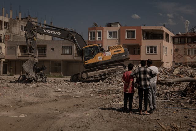 <p>Residents of a building in Samandag that was demolished watch as the rubble is sorted and removed </p>