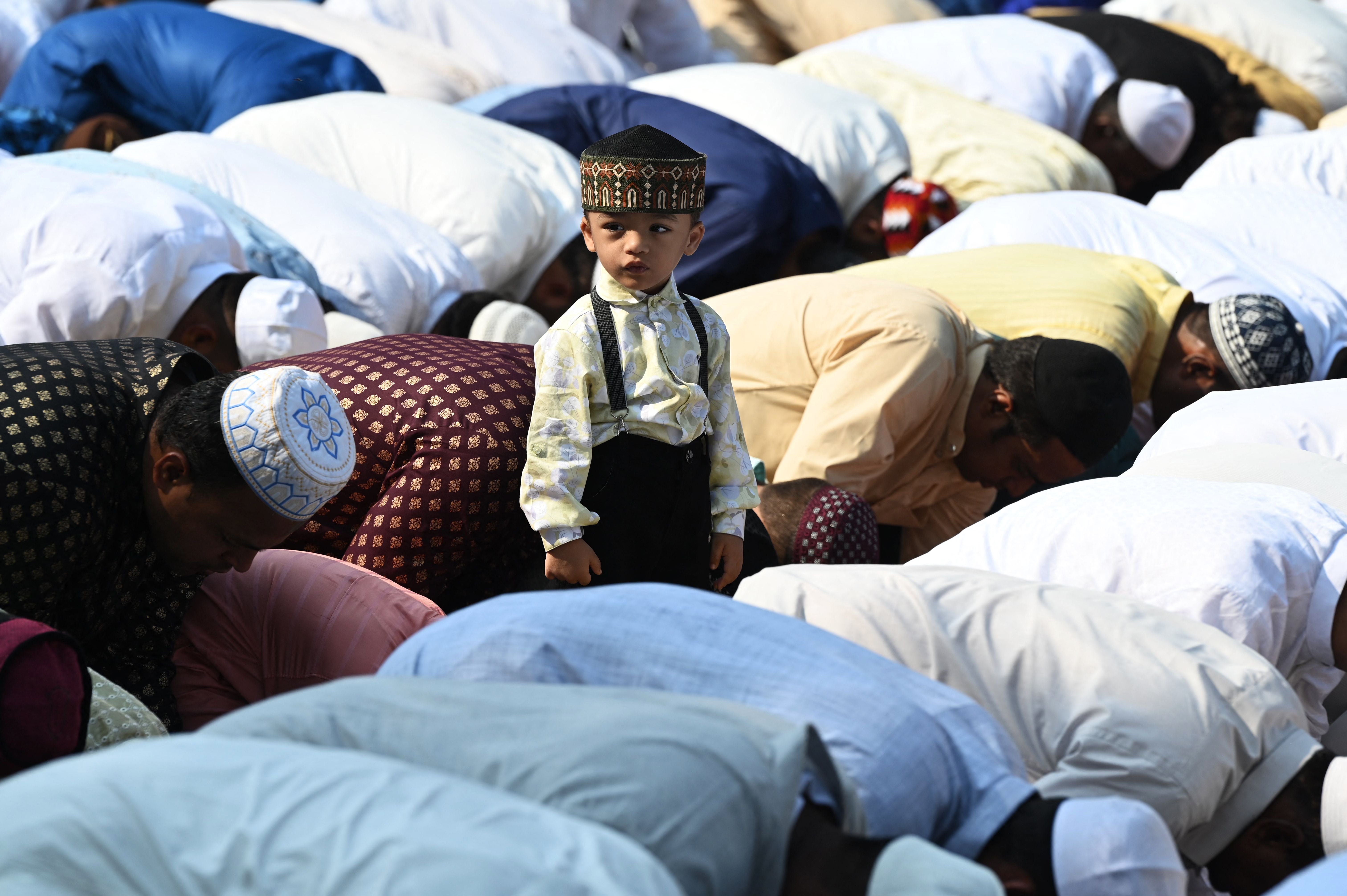 A boy stands amid Muslim devotees offering a special morning prayer to start the Eid al-Fitr festival in Hyderabad on 22 April