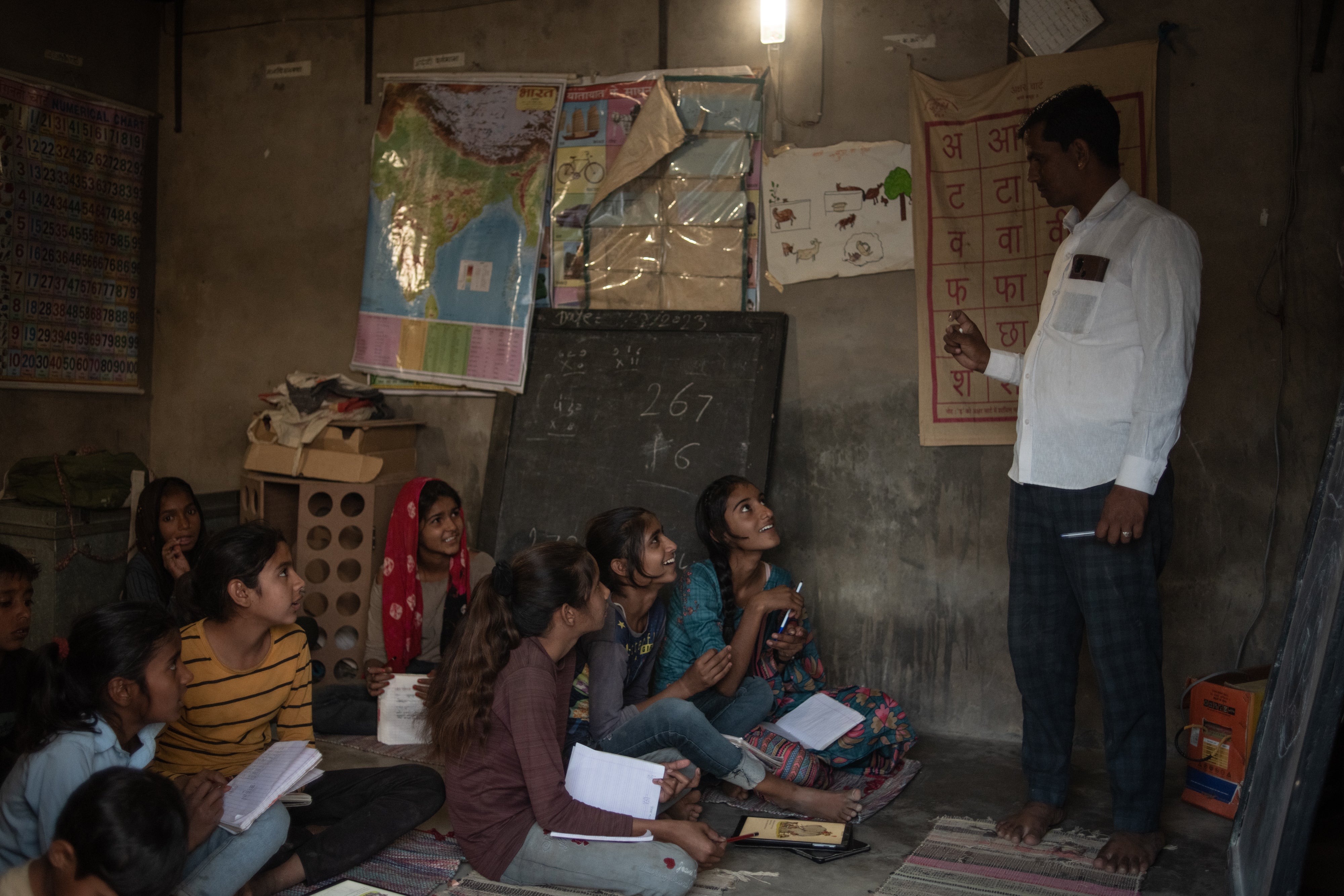 Indian school children attend a lesson at a ‘night school’, which runs in the evenings using light generated by solar power and enables children to study longer and catch up on lessons on 25 March