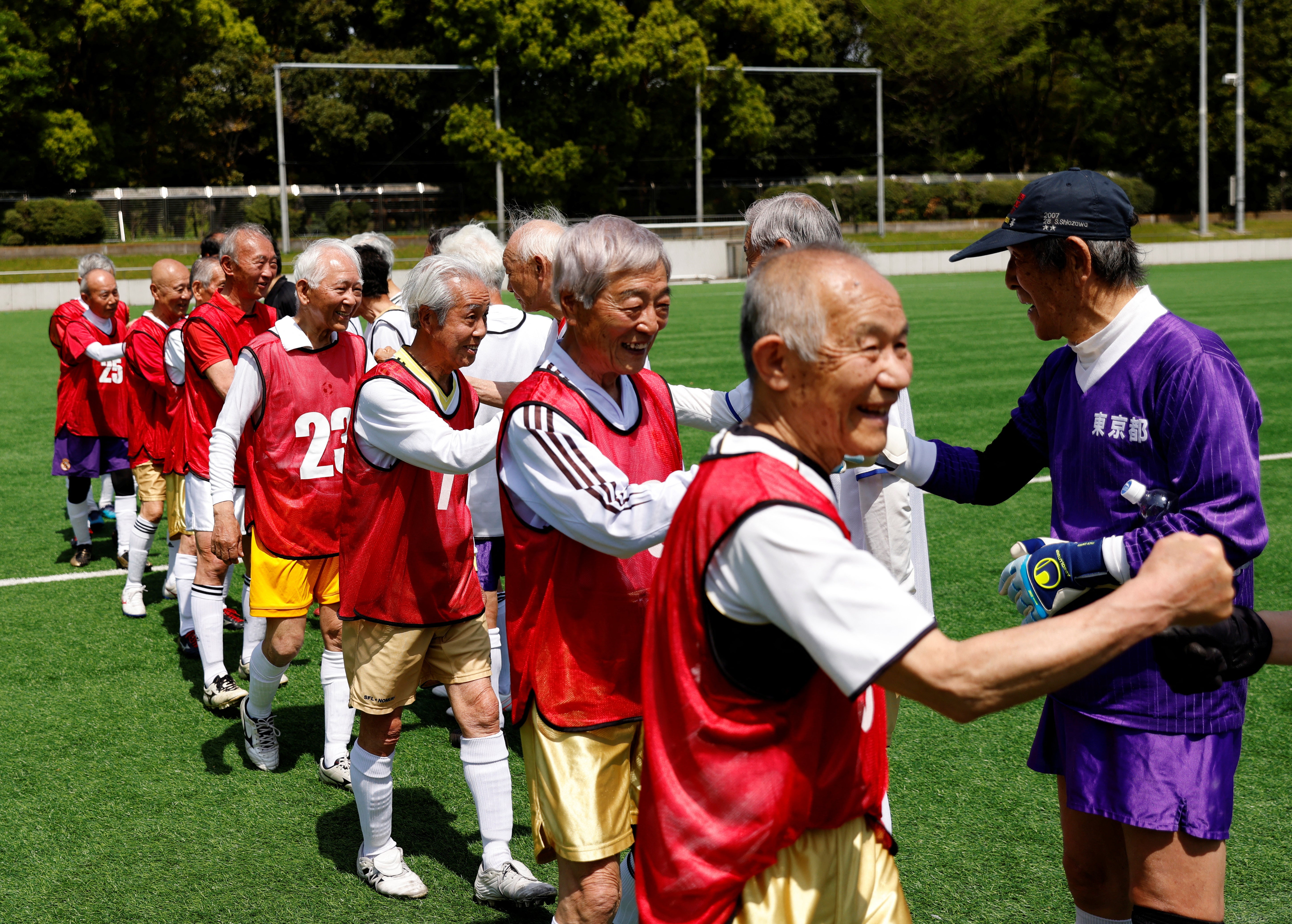 Red Star’s midfielder Mutsuhiko Nomura, 83, and White Bear’s goalkeeper Shingo Shiozawa, 93, greet their opponents at the SFL (Soccer For Life) 80 League opening match in Tokyo, Japan