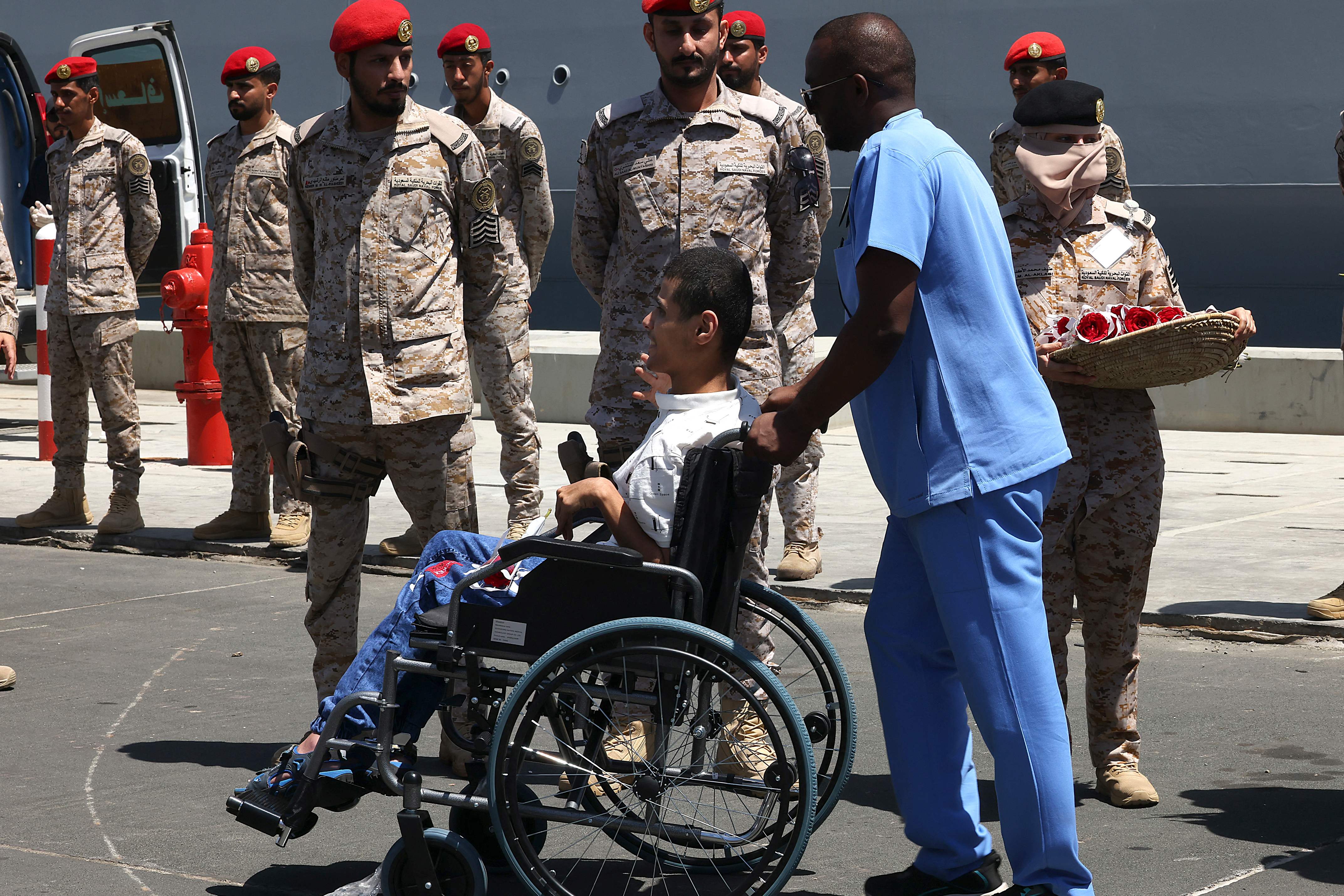 A Saudi medic assists the disabled son of Sudanese Badriah al-Sayed (not pictured) upon arrival in Jeddah on April 30, 2023 following a rescue operation from Port Sudan.