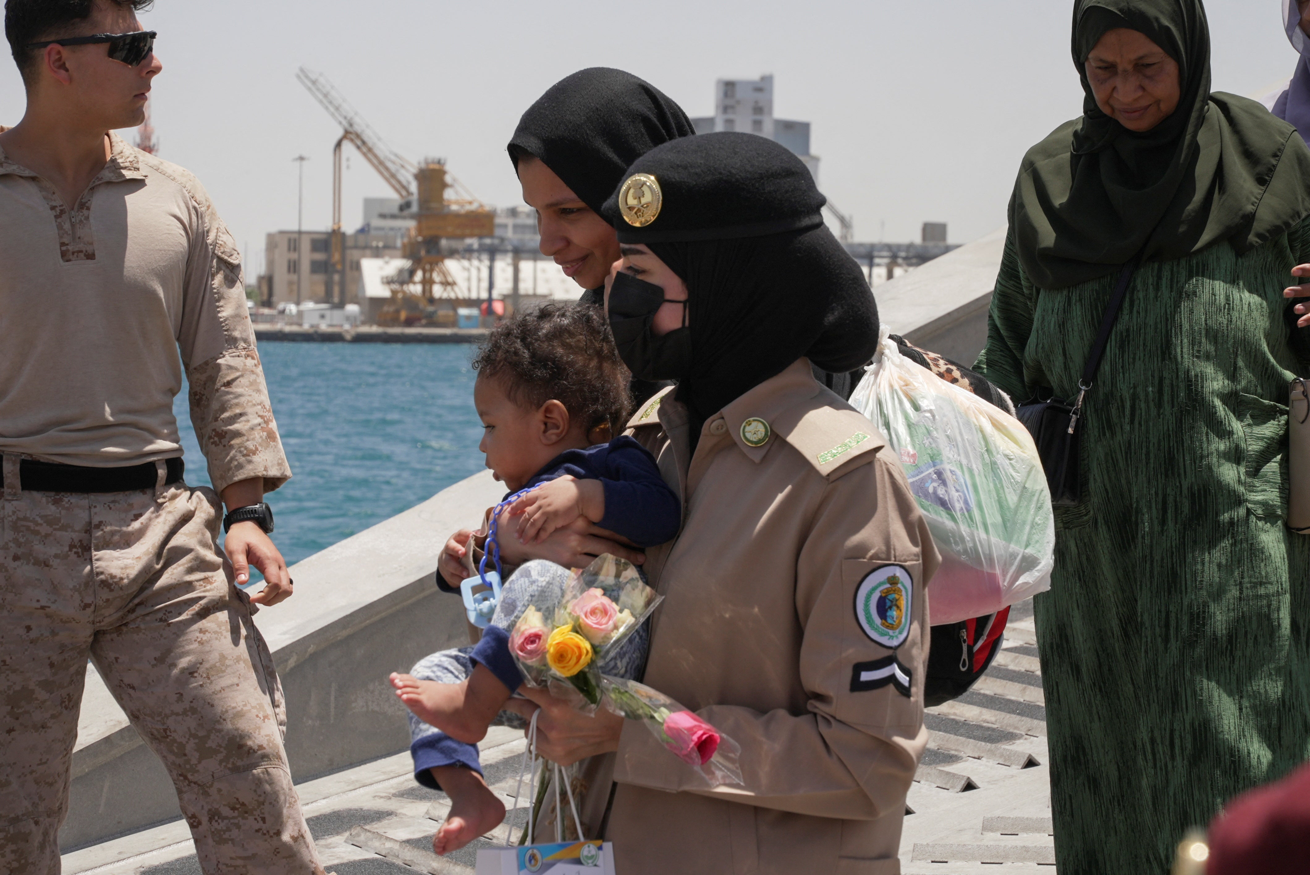 A Saudi Royal Navy female officer helps a woman disembark from the U.S. Navy fast transport ship