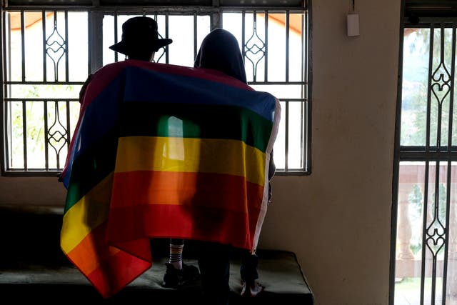 <p>A gay Ugandan couple cover themselves with a pride flag in Uganda</p>