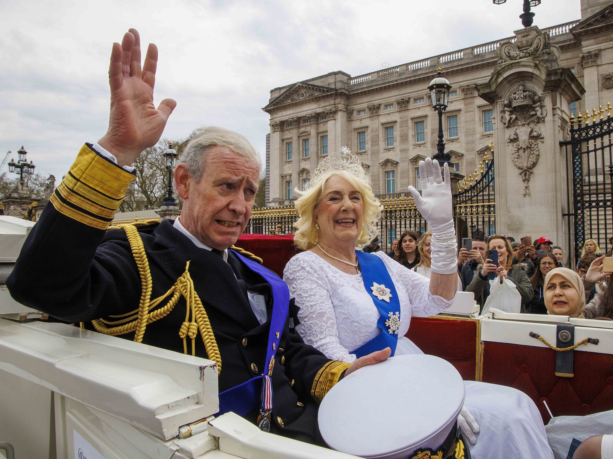 Lookalikes of King Charles III and Camilla, the Queen Consort, pass Buckingham Palace in April